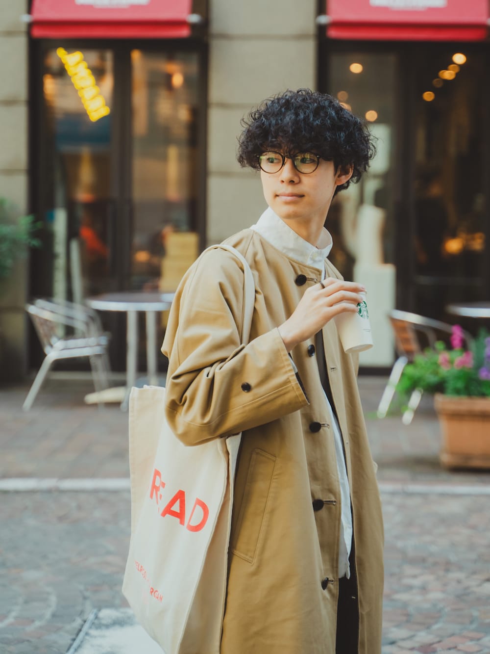 ベージュ系のノーカラーコート、ホワイト系のシャツ/ブラウス、ブルー系のデニムパンツを着用したメンズの秋コーディネートの2枚目の写真