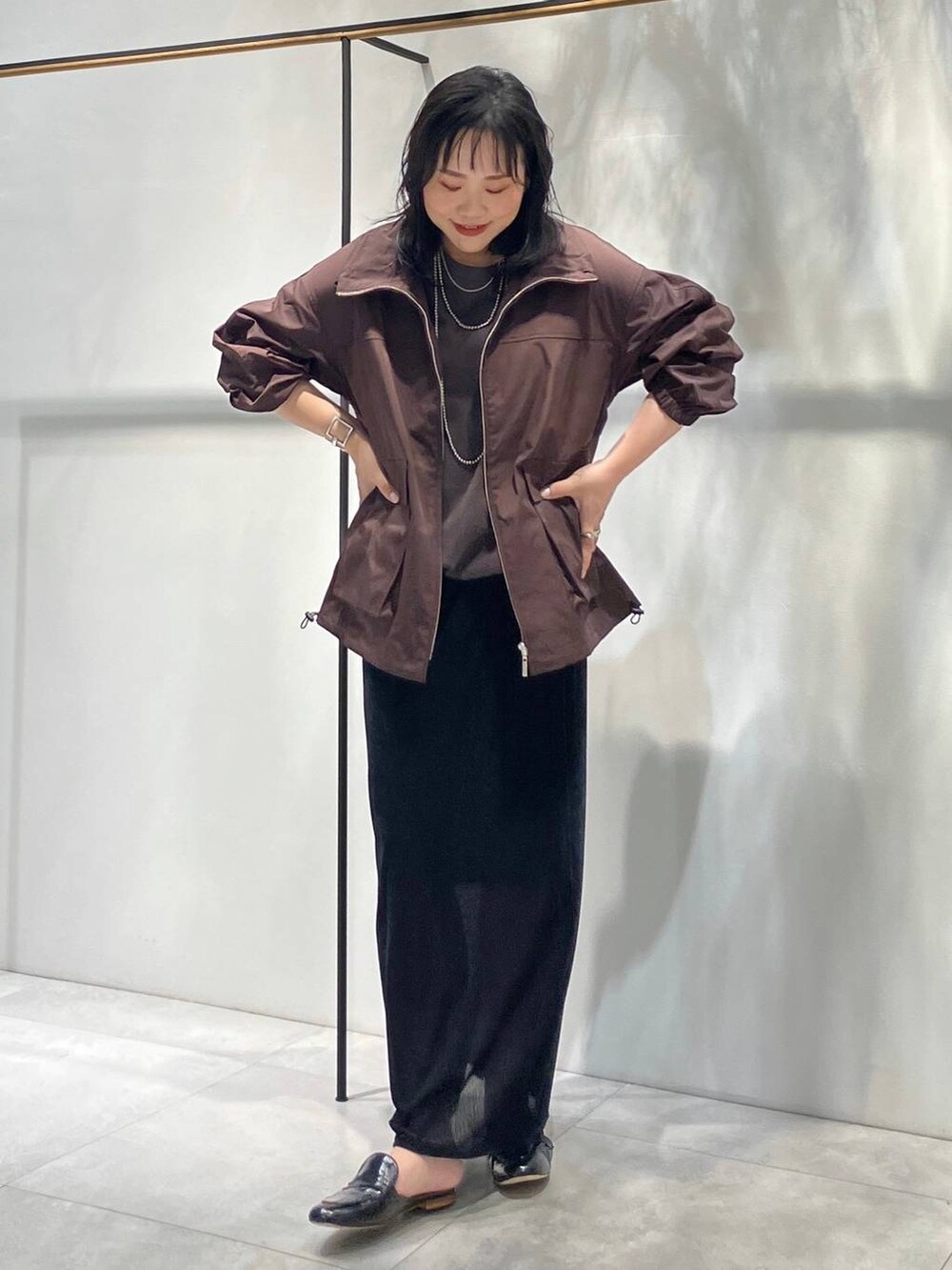 ブラック系のスカート、ブラウン系のTシャツ/カットソー、ブラウン系のブルゾンを着用したレディースの夏コーディネートの3枚目の写真