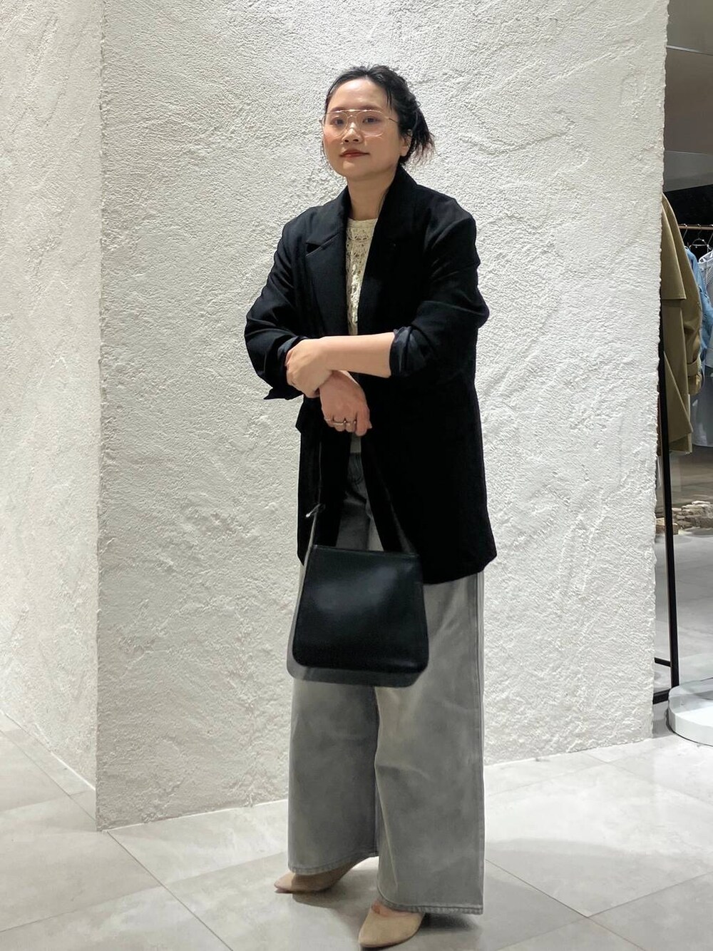 グレー系のデニムパンツ、ホワイト系のベスト、ブラック系のテーラードジャケットを着用したレディースの冬コーディネートの3枚目の写真