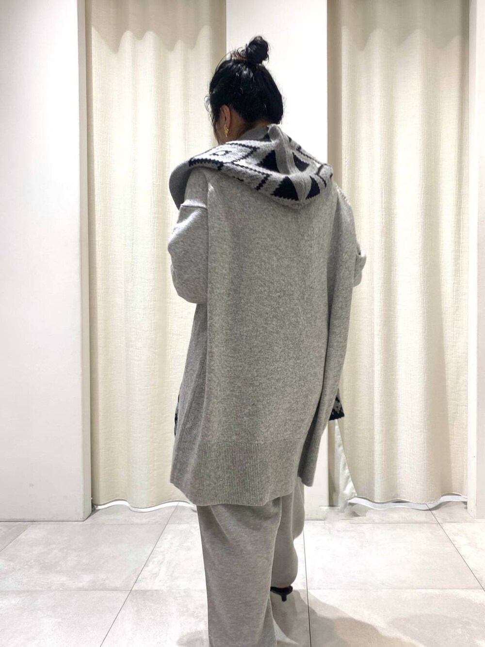 グレー系のニット/セーター、ブラウン系のトレンチコート、グレー系のスウェットパンツを着用したレディースの秋コーディネートの3枚目の写真