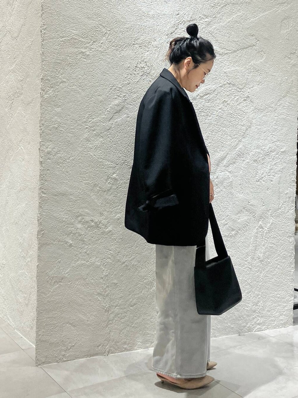 グレー系のデニムパンツ、ホワイト系のベスト、ブラック系のテーラードジャケットを着用したレディースの冬コーディネートの2枚目の写真