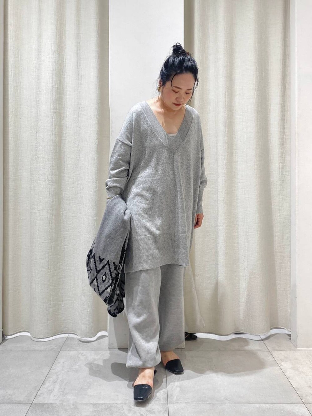 グレー系のニット/セーター、ブラウン系のトレンチコート、グレー系のスウェットパンツを着用したレディースの秋コーディネートの7枚目の写真