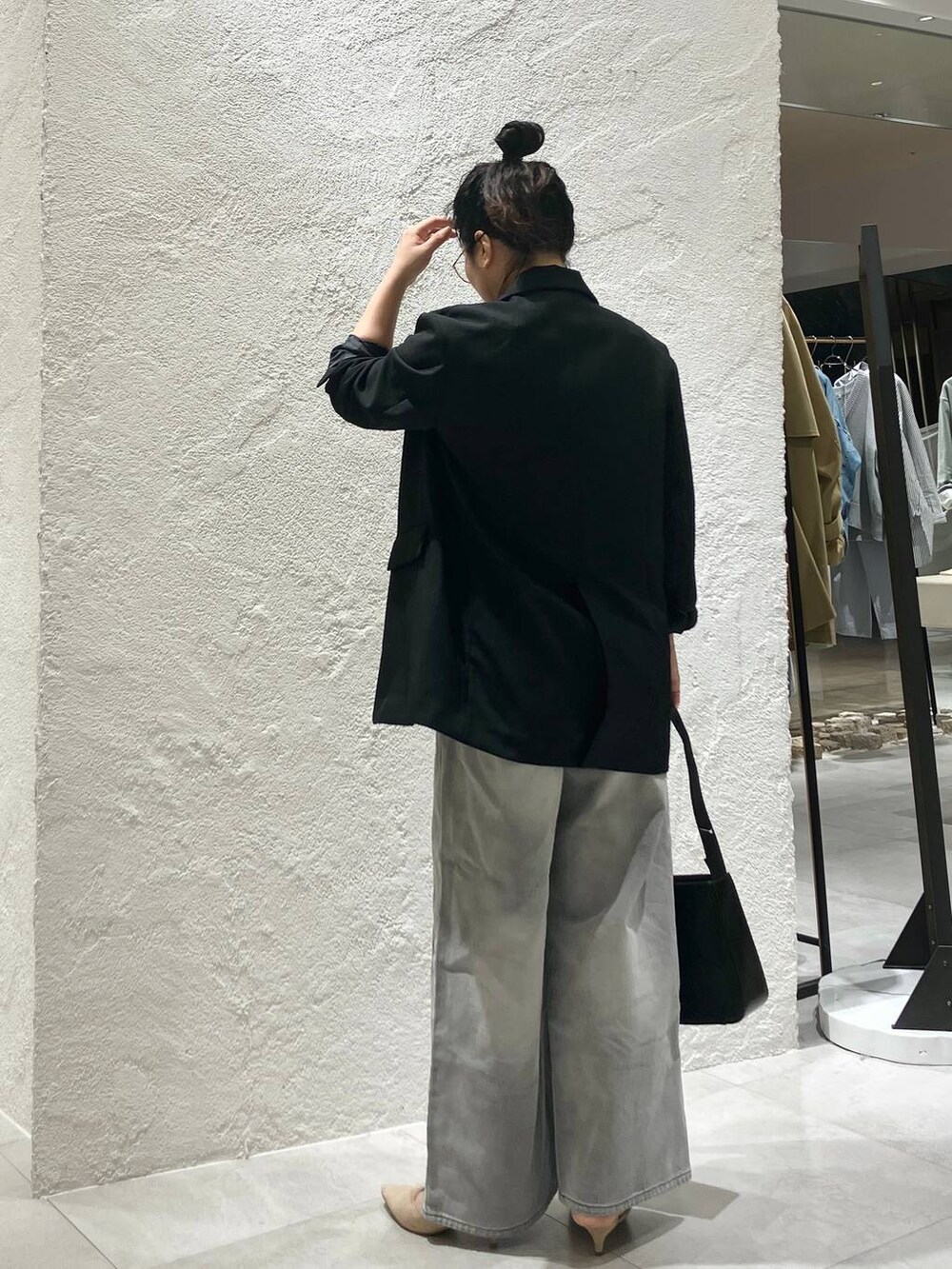 グレー系のデニムパンツ、ホワイト系のベスト、ブラック系のテーラードジャケットを着用したレディースの冬コーディネートの5枚目の写真