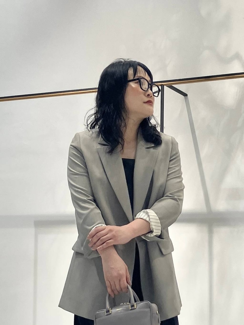 ブラック系のキャミソール、ベージュ系のボストンバッグ、ベージュ系のテーラードジャケットを着用したレディースの春コーディネートの5枚目の写真