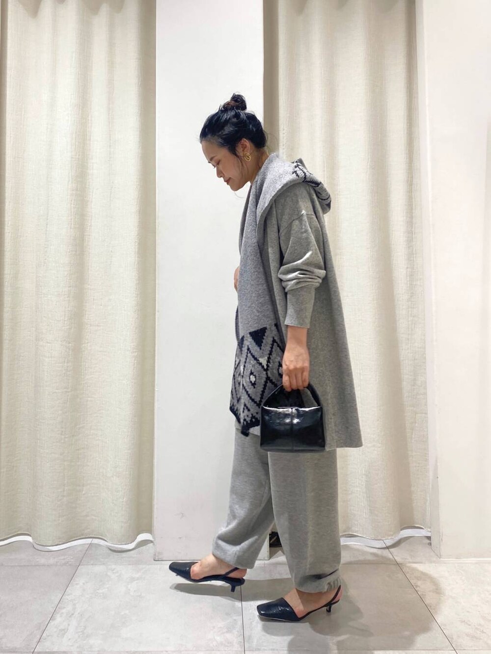 グレー系のニット/セーター、ブラウン系のトレンチコート、グレー系のスウェットパンツを着用したレディースの秋コーディネートの2枚目の写真