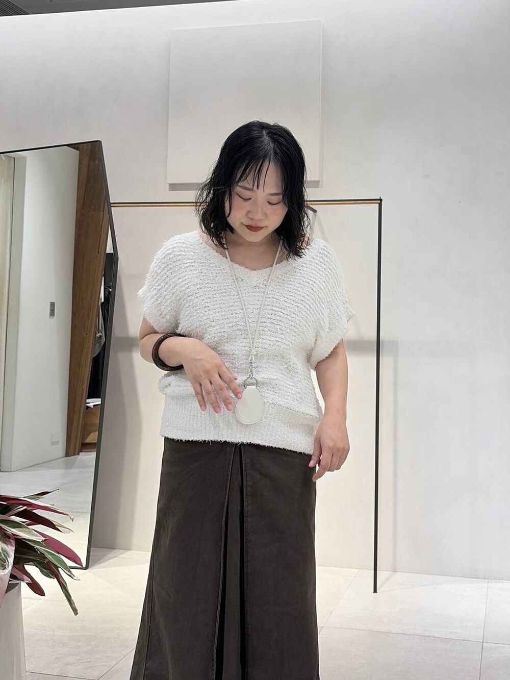 ブラウン系のスカート、ホワイト系のベスト、ブラウン系のバングル/リストバンドを着用したレディースの夏コーディネートの5枚目の写真