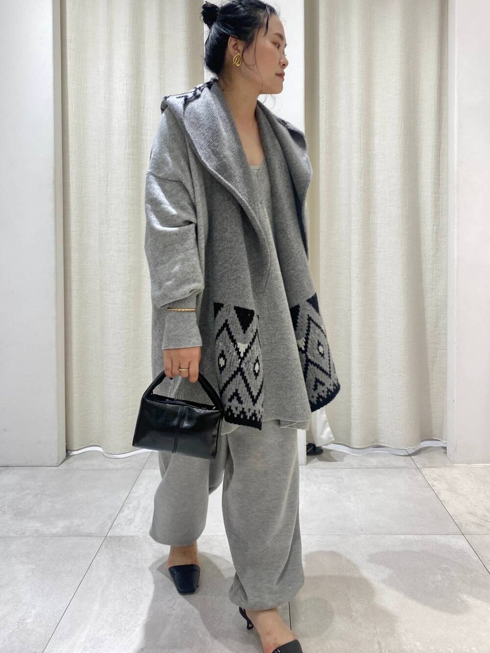 グレー系のニット/セーター、ブラウン系のトレンチコート、グレー系のスウェットパンツを着用したレディースの秋コーディネートの4枚目の写真