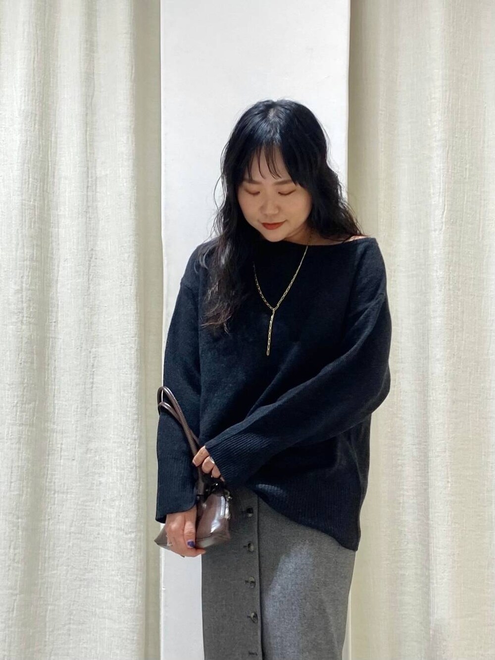 ブラック系のキャミソール、ブラウン系のショルダーバッグ、グレー系のニット/セーターを着用したレディースの秋コーディネートの2枚目の写真