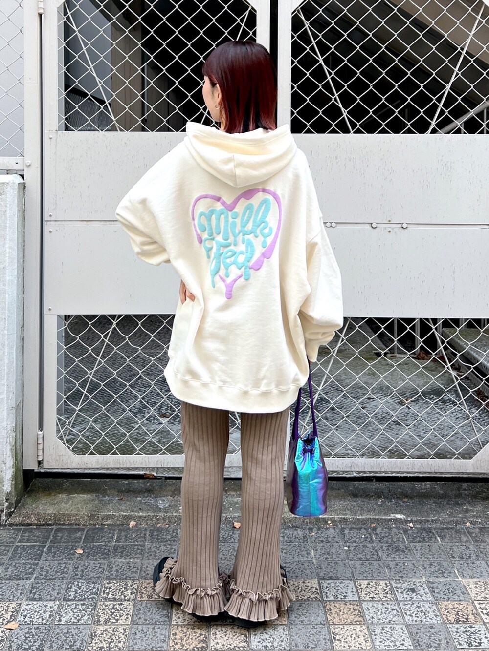 ホワイト系のパーカー、ベージュ系のその他パンツ、パープル系のショルダーバッグを着用したレディースの冬コーディネートの2枚目の写真