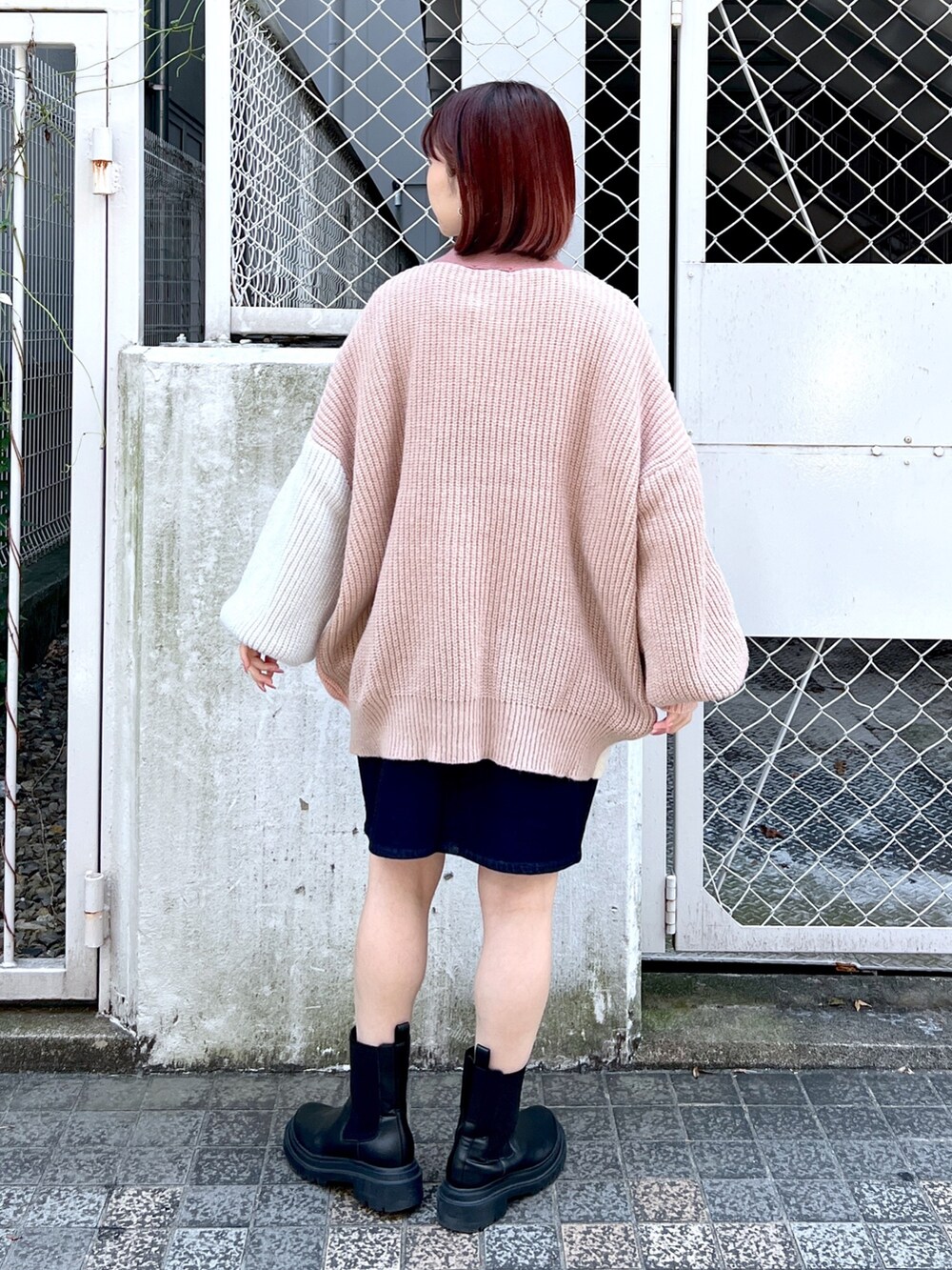 ピンク系のカーディガン/ボレロ、ブラウン系のボストンバッグ、ブルー系のデニムスカートを着用したレディースの秋コーディネートの2枚目の写真