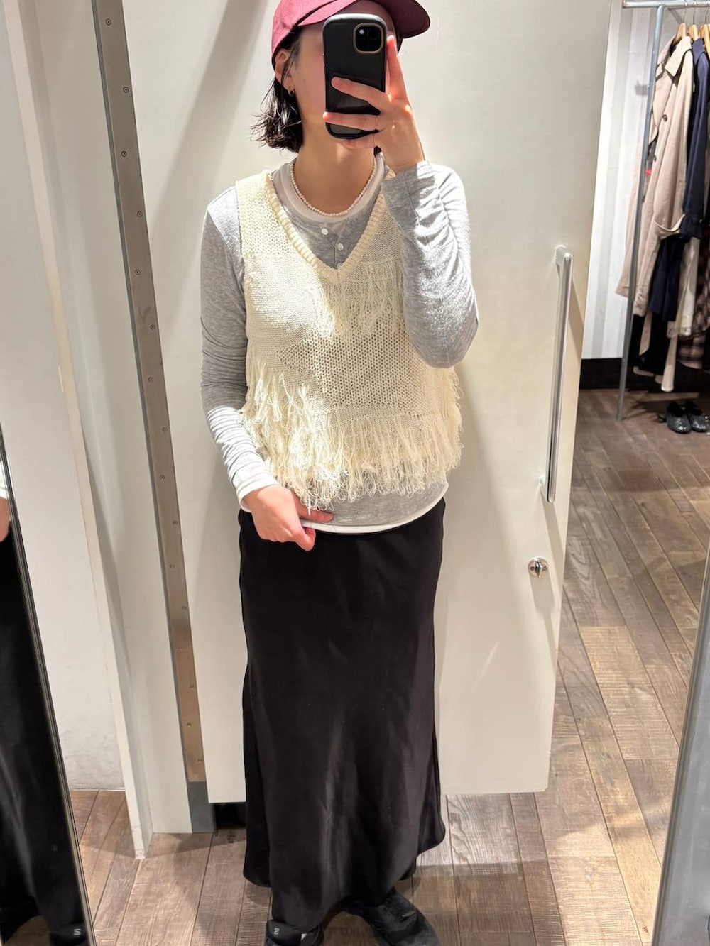 グレー系のTシャツ/カットソー、ブラック系のスカート、ホワイト系のベストを着用したレディースの春コーディネートの2枚目の写真