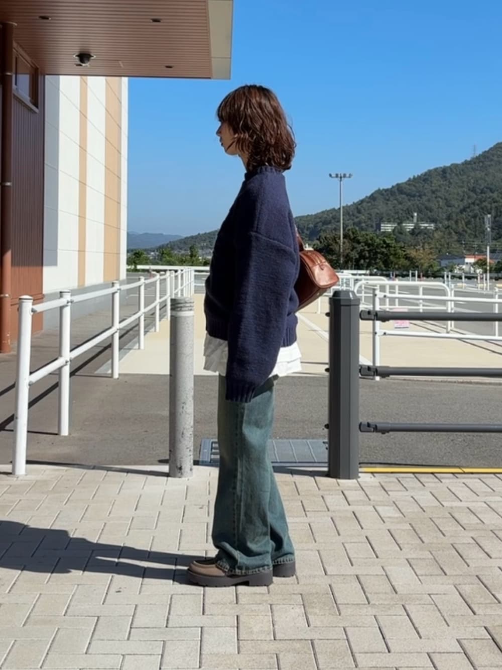 ブルー系のニット/セーター、ブルー系のデニムパンツ、ホワイト系のワンピースを着用したレディースの秋コーディネートの3枚目の写真