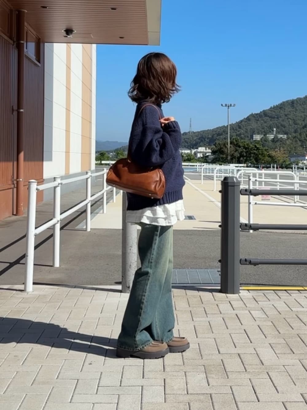 ブルー系のニット/セーター、ブルー系のデニムパンツ、ホワイト系のワンピースを着用したレディースの秋コーディネートの2枚目の写真