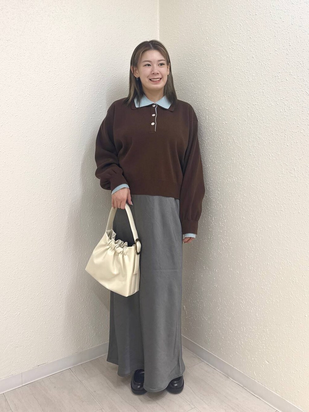 グレー系のスカート、ブラック系のローファー、ホワイト系のショルダーバッグを着用したレディースの冬コーディネートの2枚目の写真