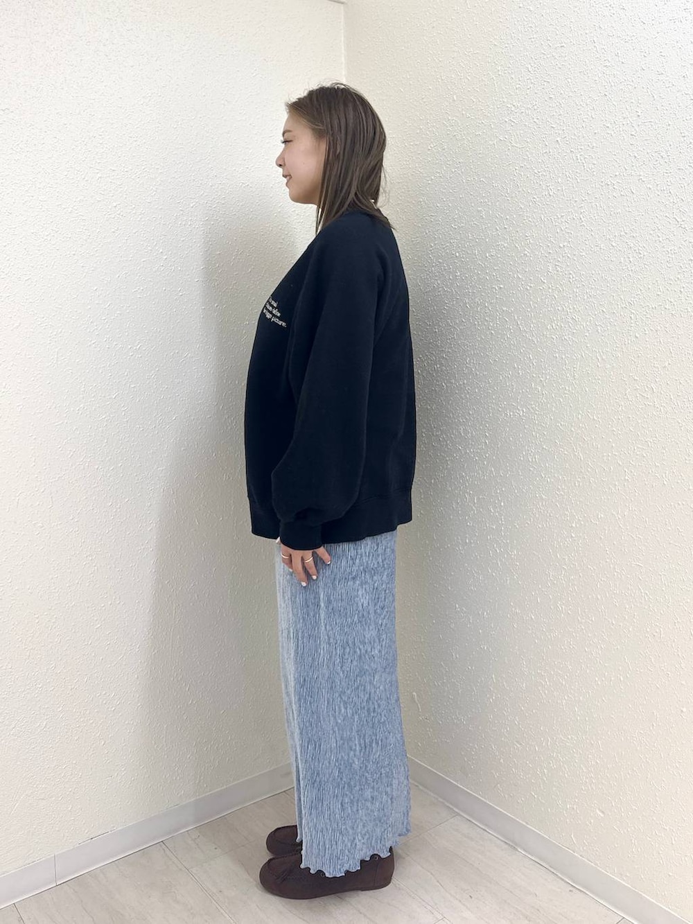 ブルー系のスカート、ブラック系のモカシン/デッキシューズ、ブラック系のスウェットを着用したレディースの冬コーディネートの3枚目の写真