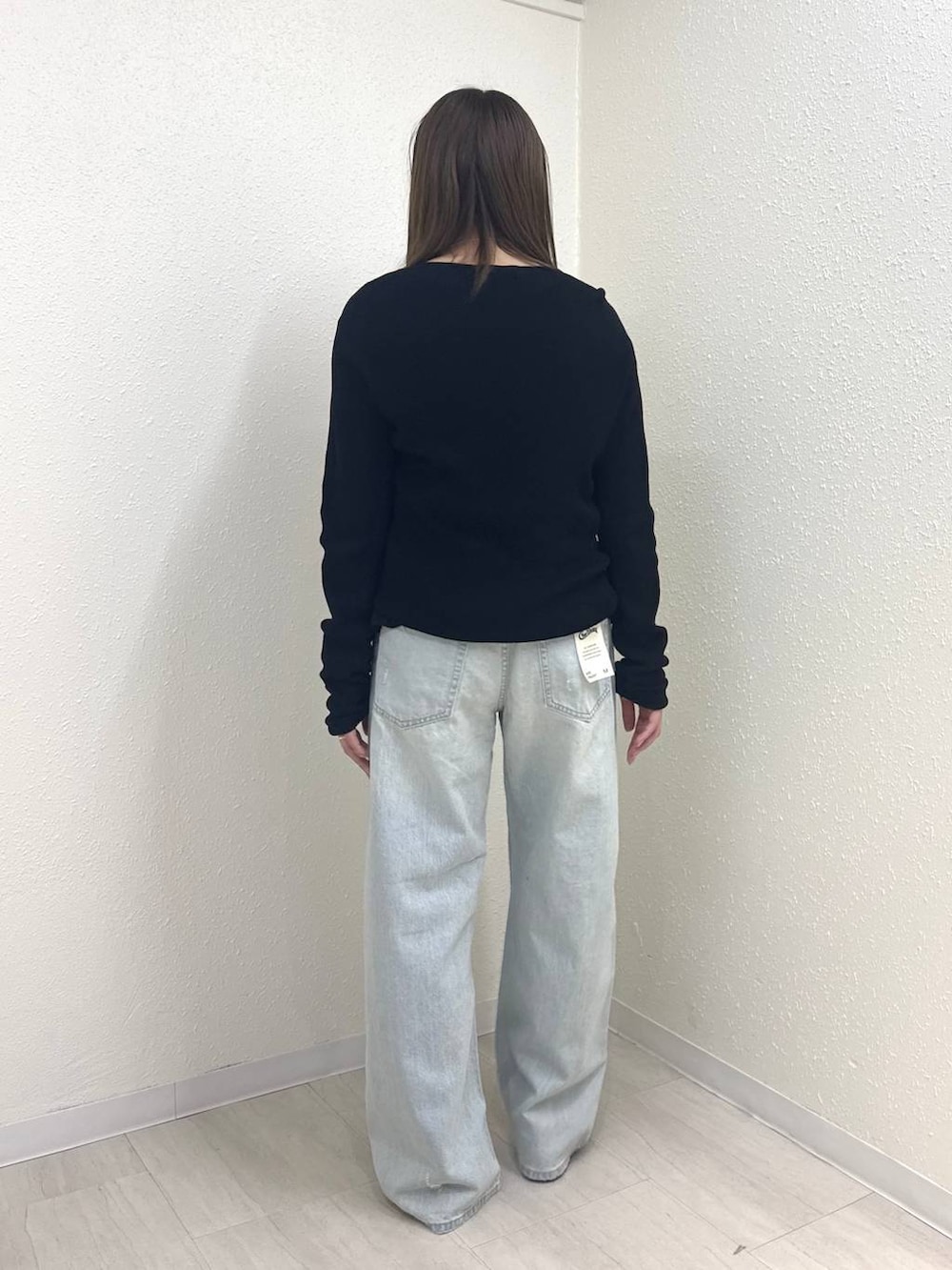 ブラック系のニット/セーター、ブルー系のデニムパンツ、ブラック系のTシャツ/カットソーを着用したレディースの春コーディネートの4枚目の写真