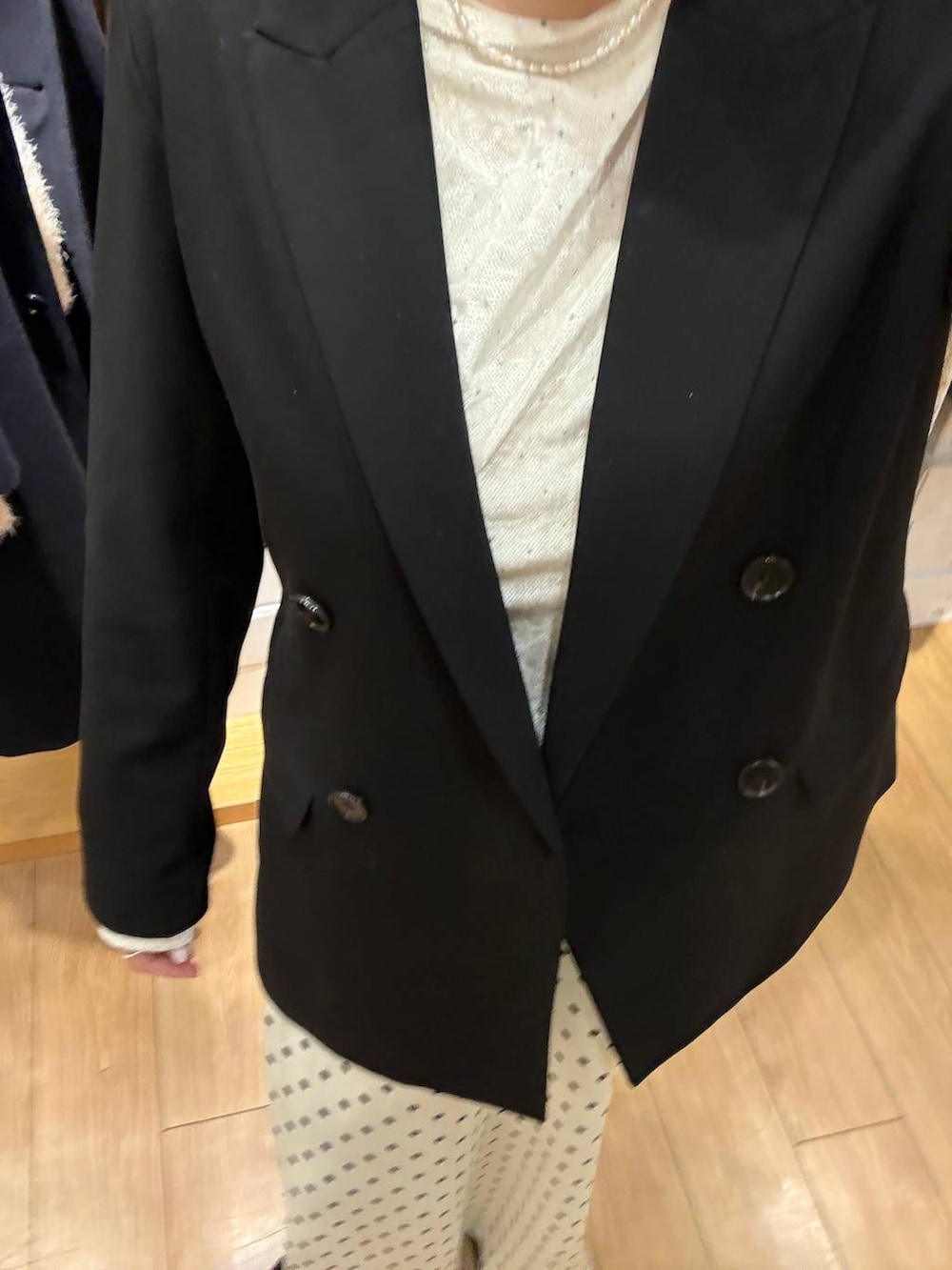 ホワイト系のスカート、ブラック系のテーラードジャケット、ホワイト系のTシャツ/カットソーを着用したレディースの冬コーディネートの3枚目の写真