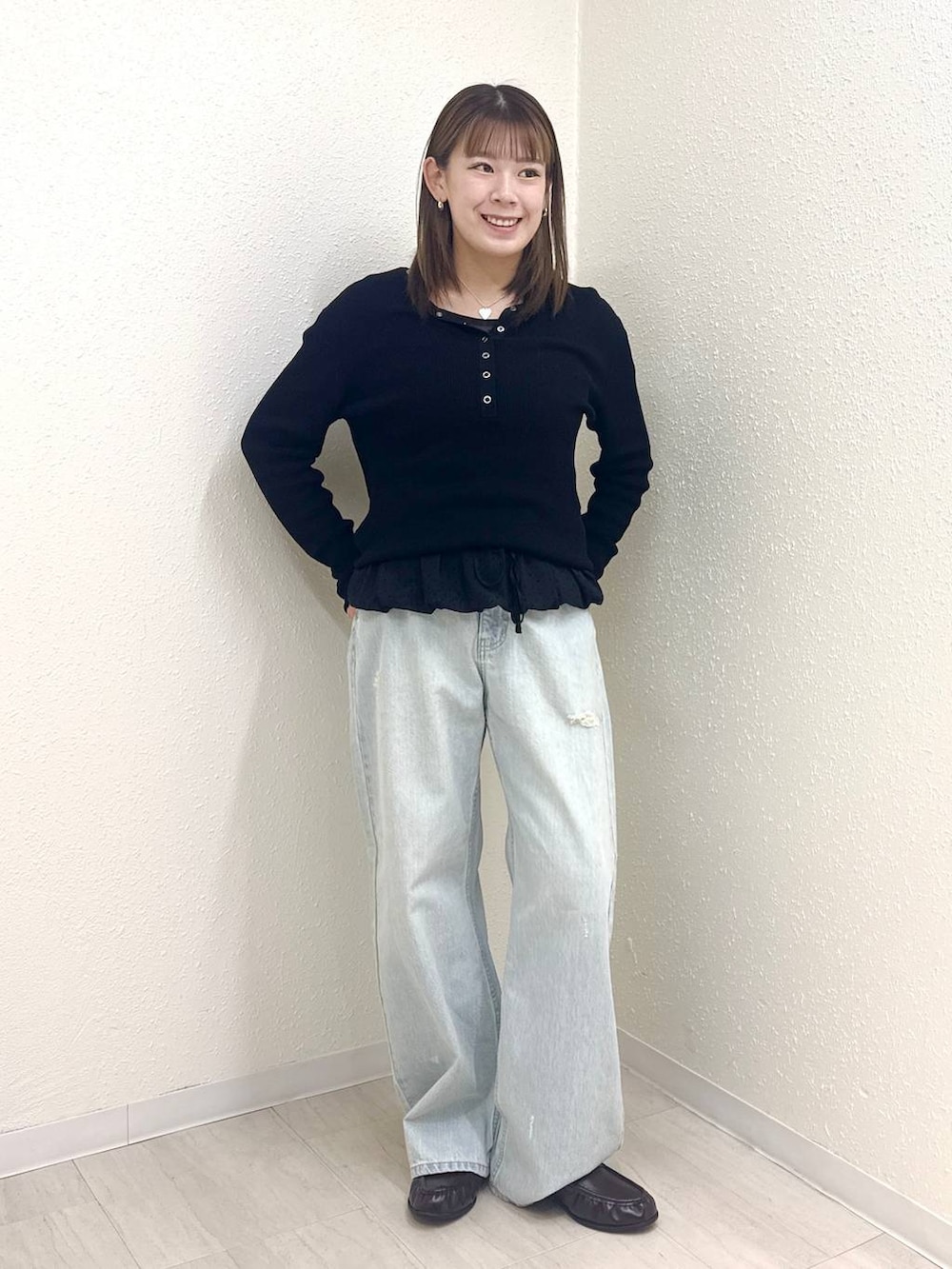 ブラック系のニット/セーター、ブルー系のデニムパンツ、ブラック系のTシャツ/カットソーを着用したレディースの春コーディネートの2枚目の写真