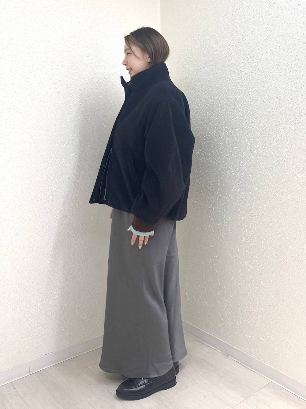 グレー系のスカート、ブラック系のローファー、ブラック系のブルゾンを着用したレディースの冬コーディネートの3枚目の写真