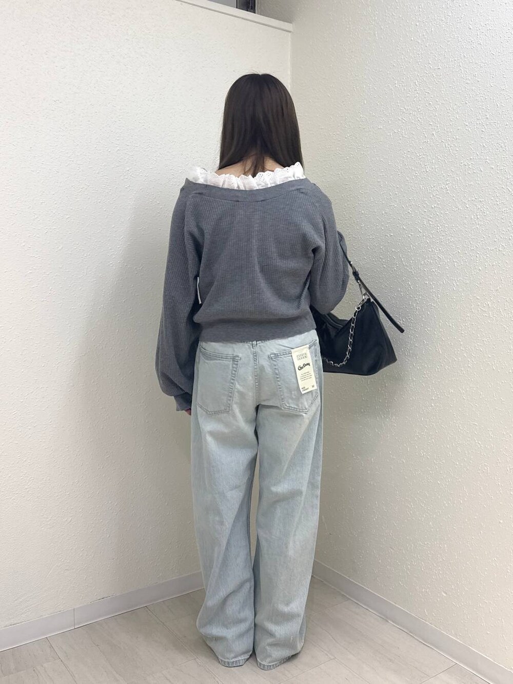 ブルー系のデニムパンツ、ブラック系のショルダーバッグ、グレー系のカーディガン/ボレロを着用したレディースの春コーディネートの3枚目の写真