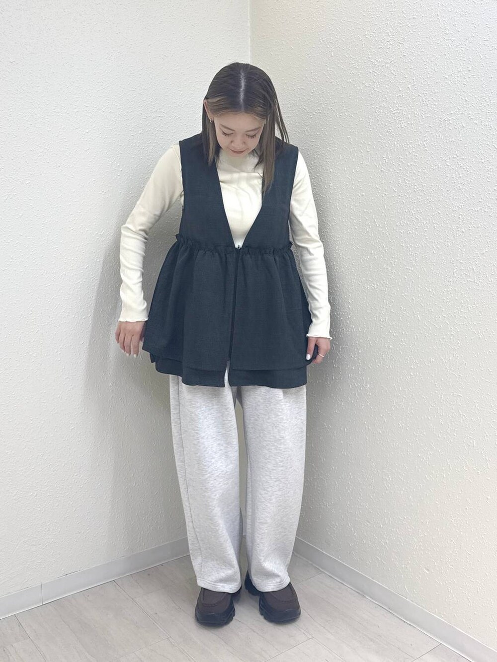 グレー系のスウェットパンツ、グレー系のベスト、ブラウン系のローファーを着用したレディースの冬コーディネートの2枚目の写真