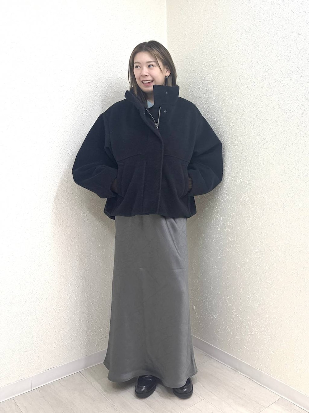 グレー系のスカート、ブラック系のローファー、ブラック系のブルゾンを着用したレディースの冬コーディネートの2枚目の写真