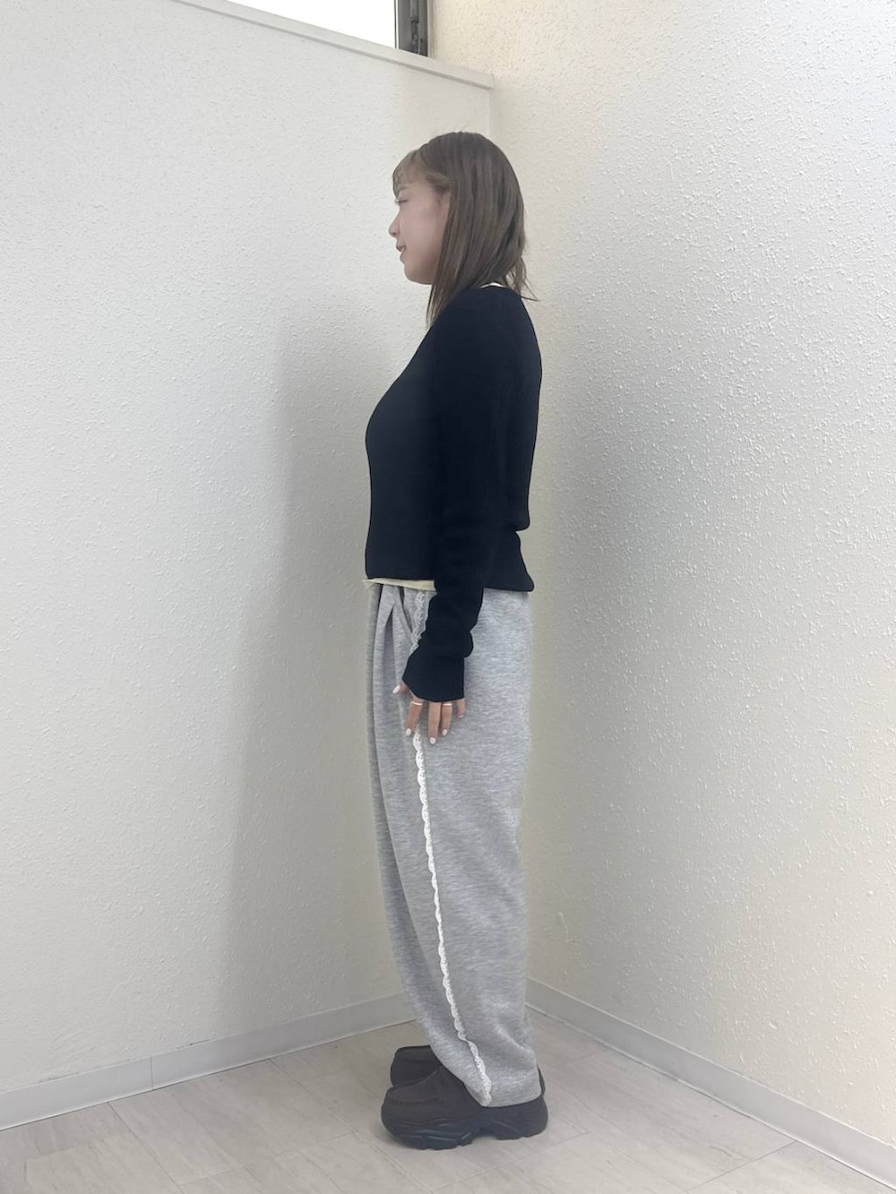 グレー系のスウェットパンツ、ブラック系のニット/セーター、イエロー系のTシャツ/カットソーを着用したレディースの冬コーディネートの3枚目の写真