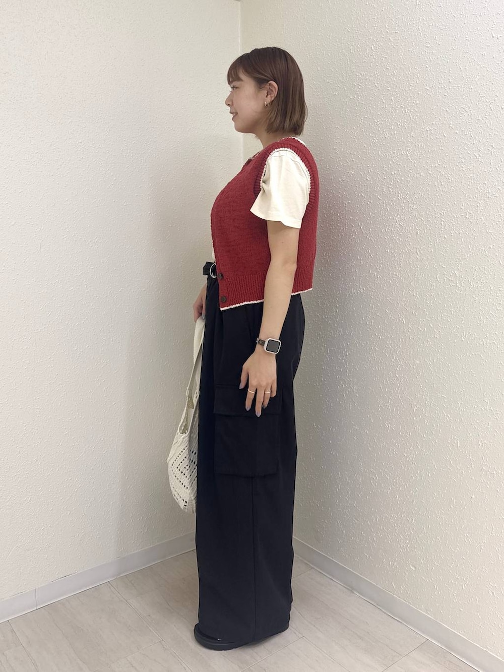 ホワイト系のサンダル、レッド系のベスト、ブラック系のカーゴパンツを着用したレディースの夏コーディネートの3枚目の写真