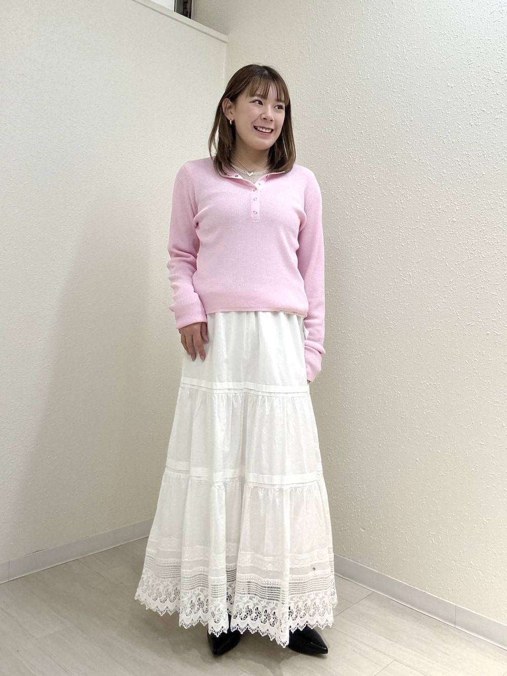 ブラック系のパンプス、ピンク系のニット/セーター、ホワイト系のスカートを着用したレディースの春コーディネートの2枚目の写真