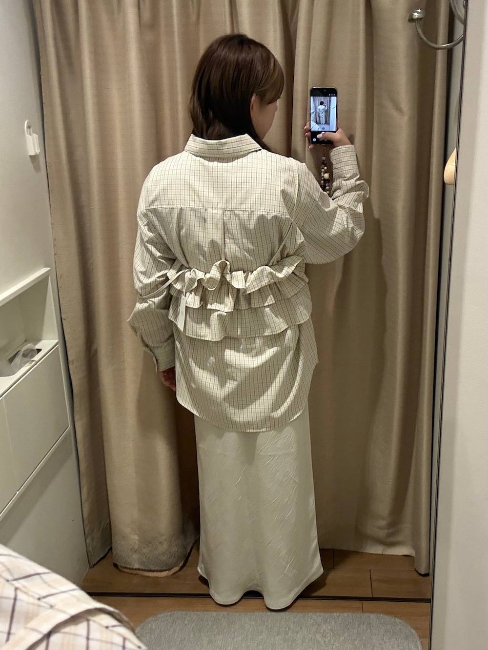 ホワイト系のスカート、ベージュ系のシャツ/ブラウス、ブラウン系のキャミソールを着用したレディースの冬コーディネートの2枚目の写真