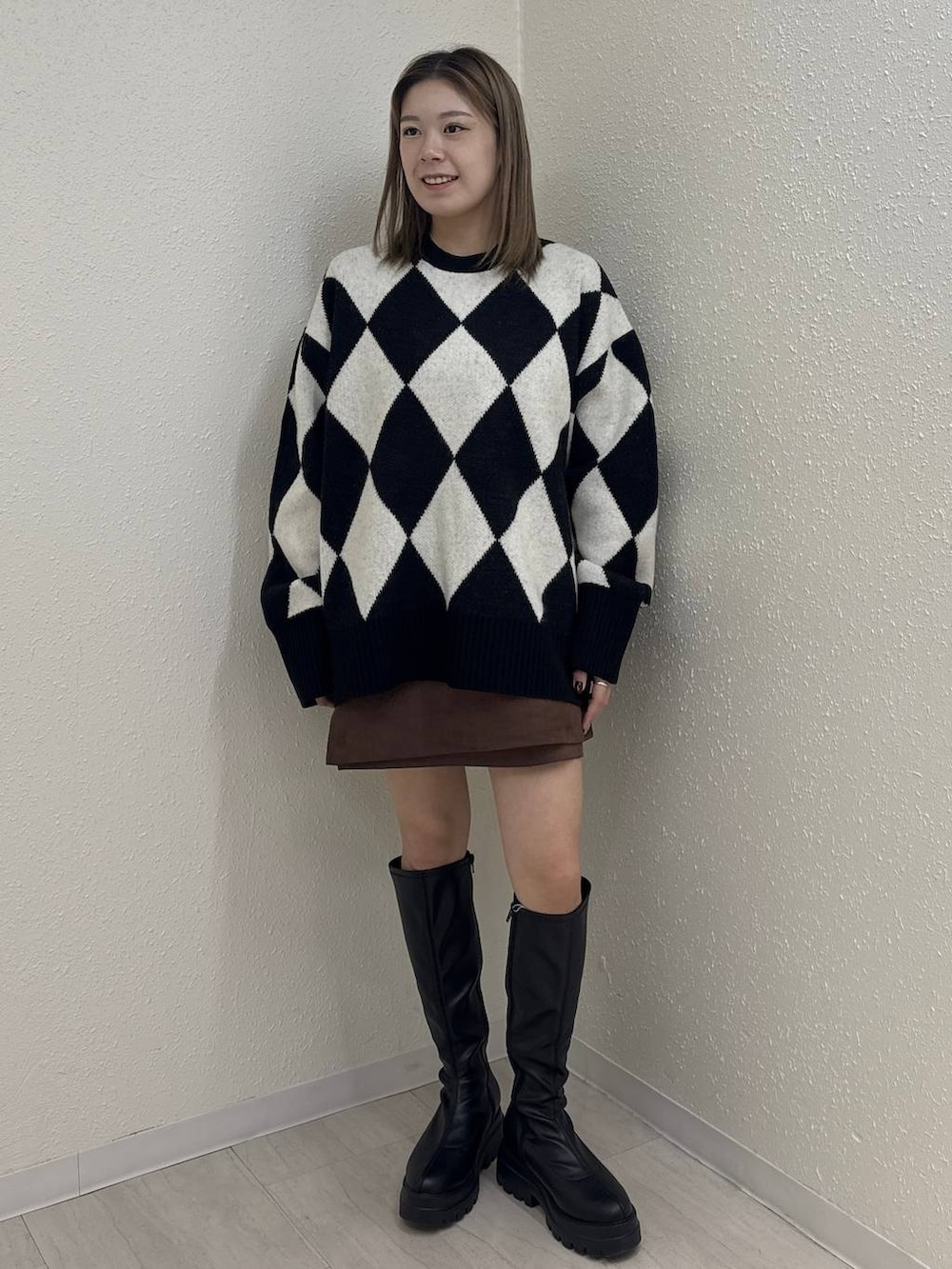 ブラウン系のスカート、ブラック系のニット/セーター、ブラック系のブーツを着用したレディースの冬コーディネートの2枚目の写真