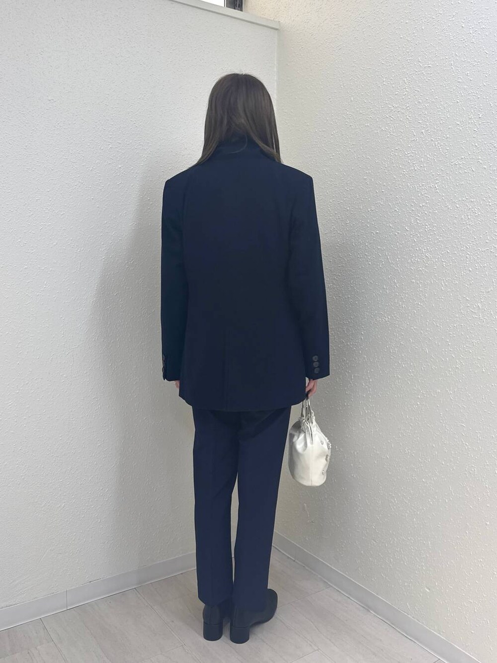 ブラック系のブーツ、ホワイト系のハンドバッグ、ブルー系のテーラードジャケットを着用したレディースの冬コーディネートの2枚目の写真