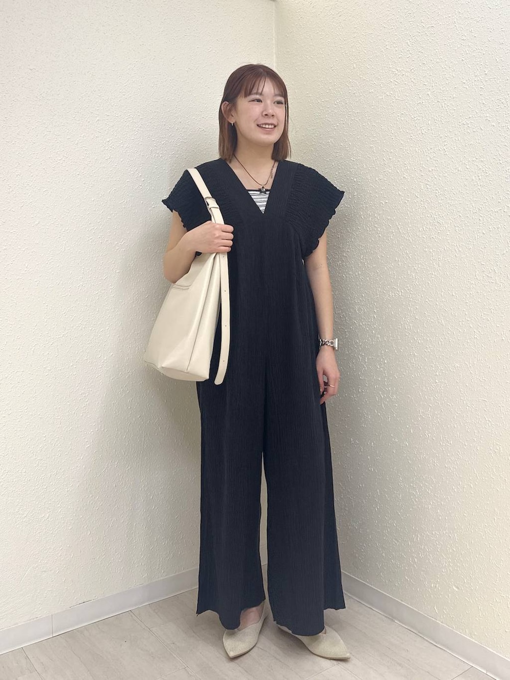 ホワイト系のショルダーバッグ、ブラック系のサロペット/オーバーオール、ホワイト系のパンプスを着用したレディースの春コーディネートの2枚目の写真