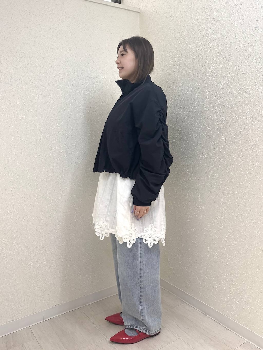 レッド系のパンプス、ブルー系のデニムパンツ、ブラック系のブルゾンを着用したレディースの春コーディネートの2枚目の写真