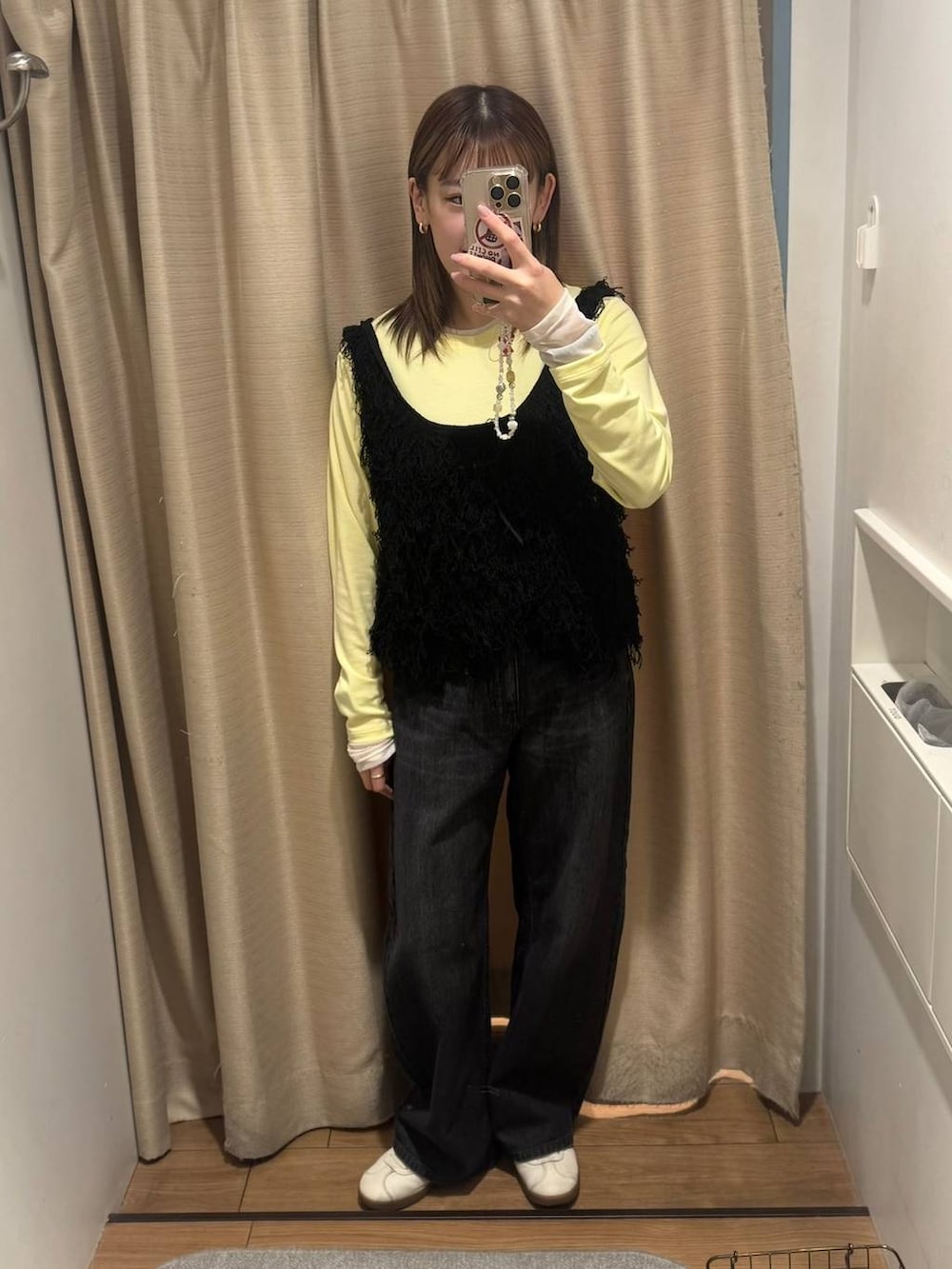 ブラック系のデニムパンツ、ブラック系のベスト、イエロー系のTシャツ/カットソーを着用したレディースの春コーディネートの2枚目の写真