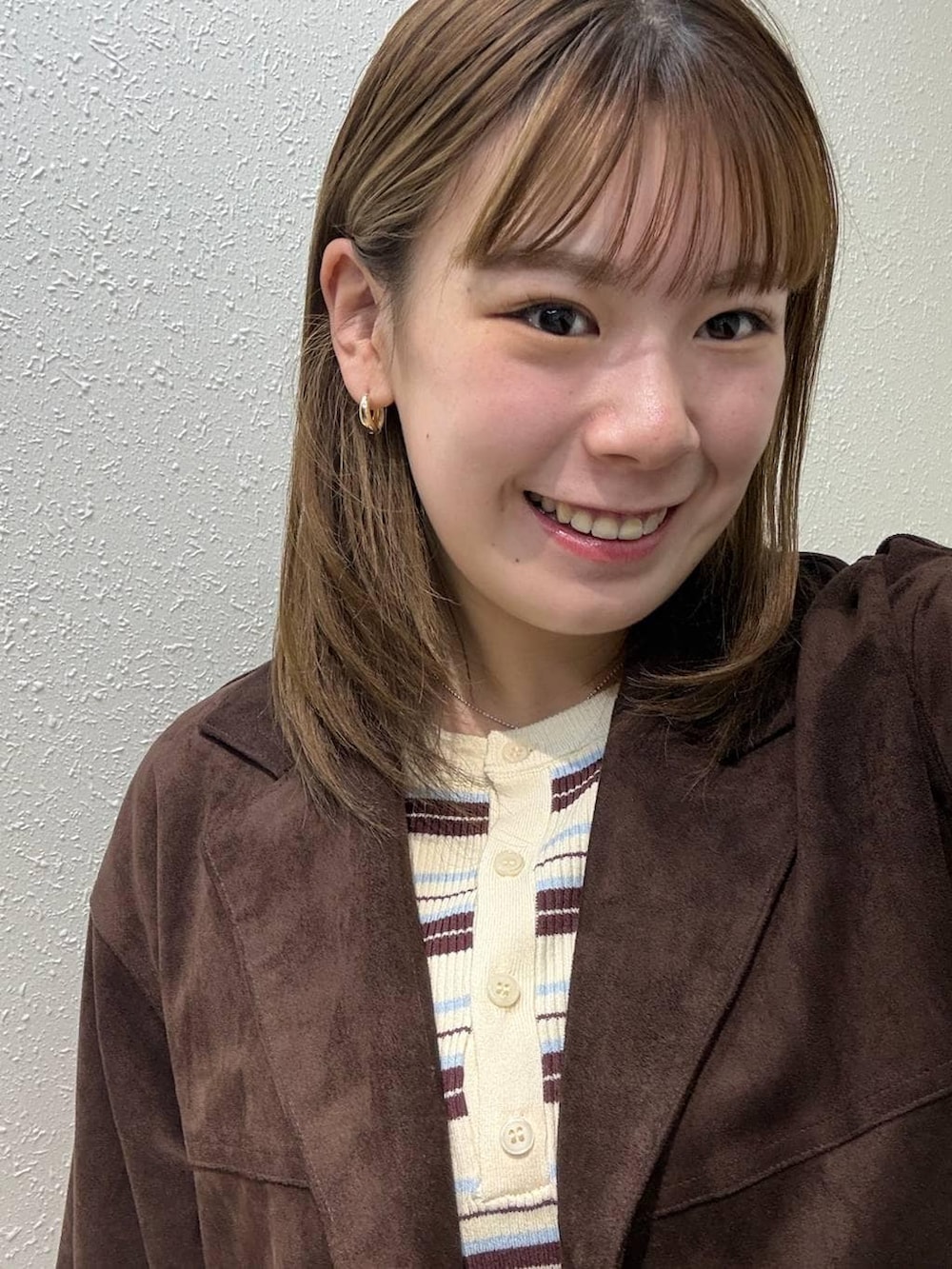 ブラウン系のテーラードジャケット、ホワイト系のニット/セーターを着用したレディースの春コーディネートの2枚目の写真