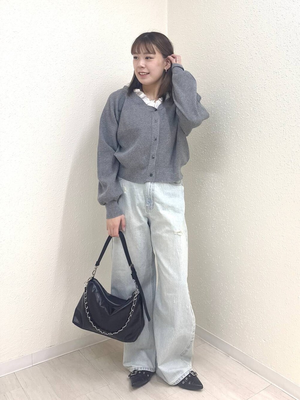ブルー系のデニムパンツ、ブラック系のショルダーバッグ、グレー系のカーディガン/ボレロを着用したレディースの春コーディネートの2枚目の写真