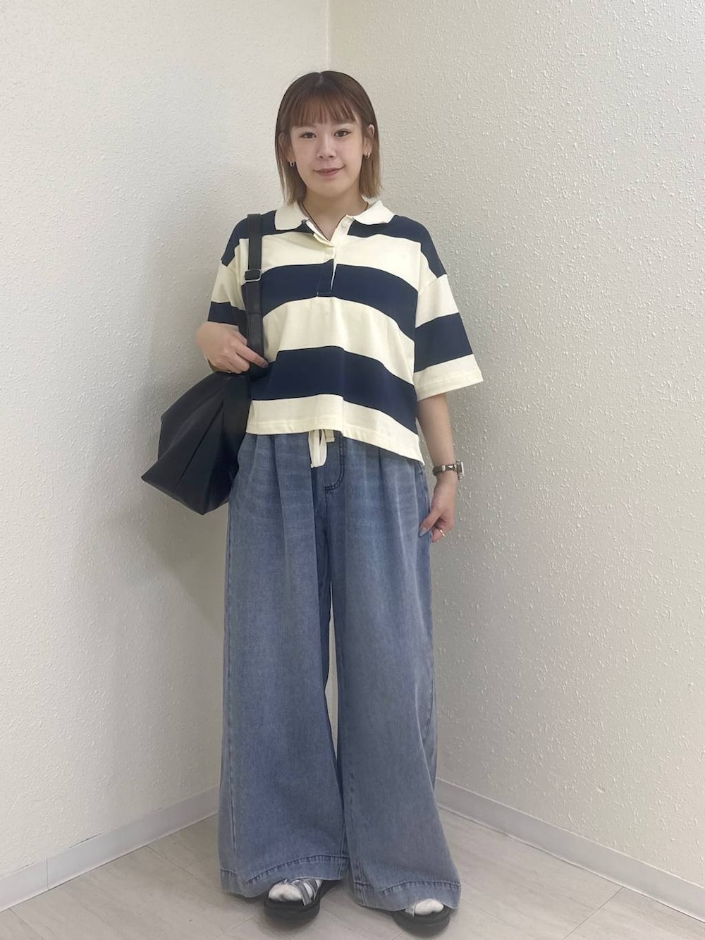 シルバー系のサンダル、ブラック系のショルダーバッグ、ブルー系のデニムパンツを着用したレディースの夏コーディネートの3枚目の写真