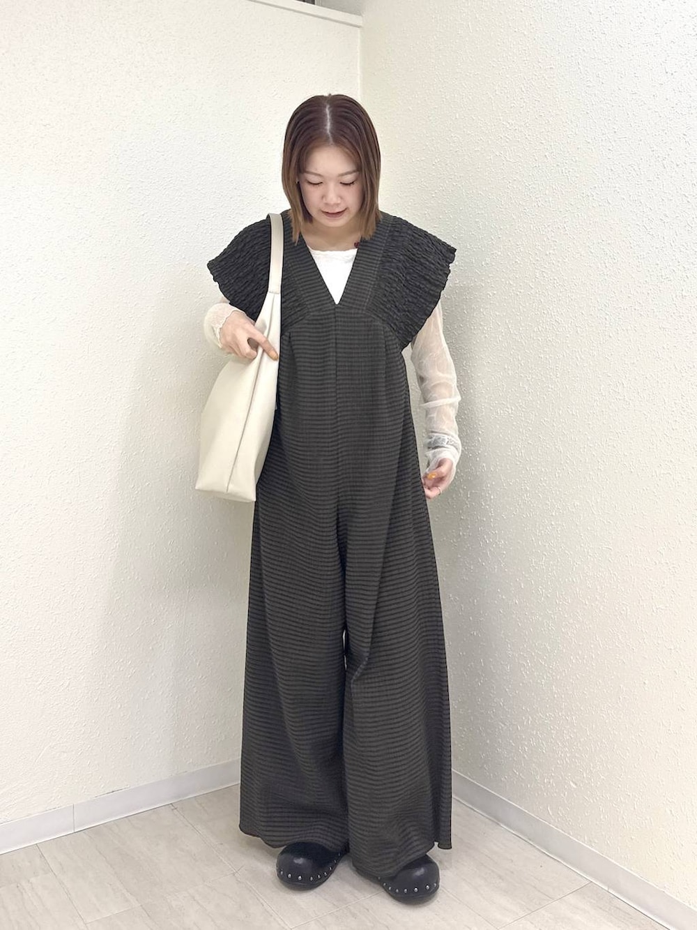 ホワイト系のショルダーバッグ、ブラウン系のサロペット/オーバーオール、ブラック系のサンダルを着用したレディースの春コーディネートの2枚目の写真