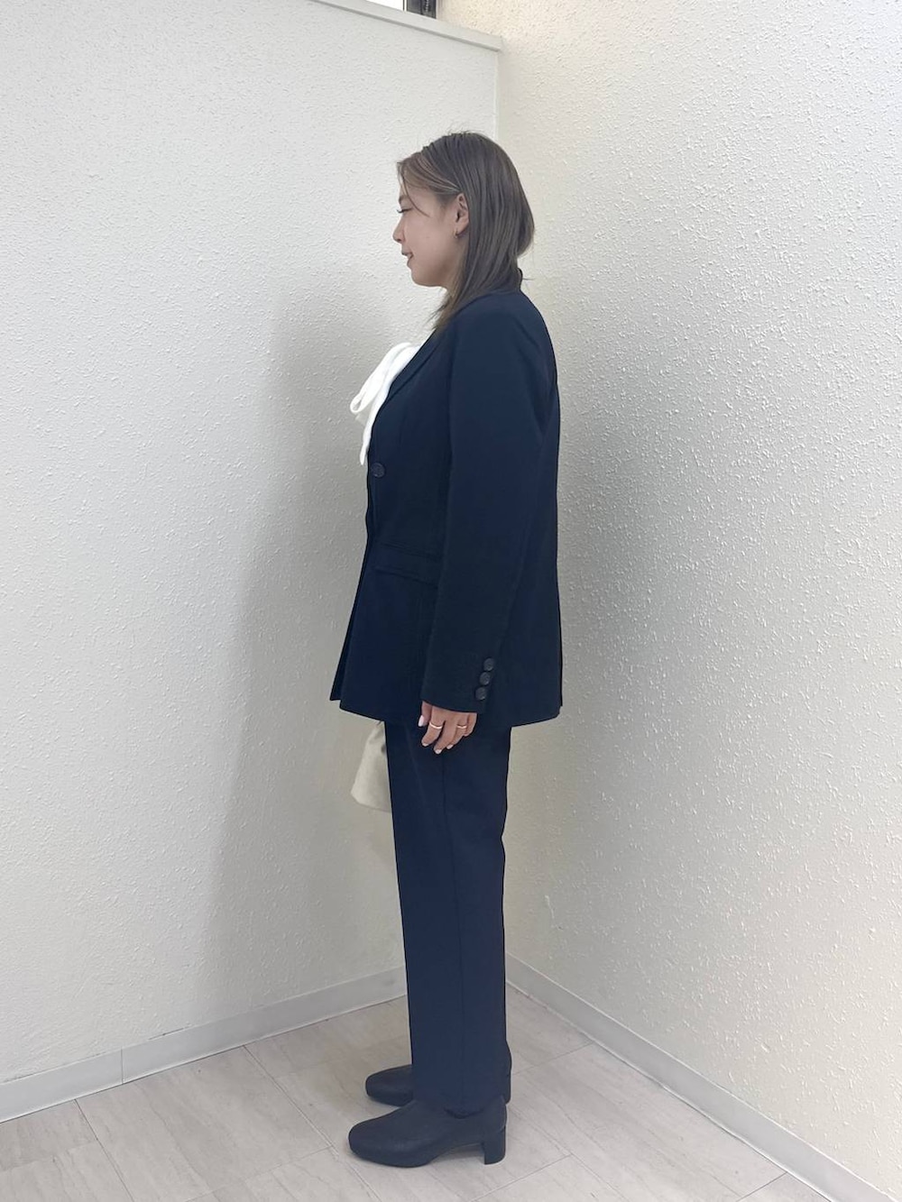 ブラック系のブーツ、ホワイト系のハンドバッグ、ブルー系のテーラードジャケットを着用したレディースの冬コーディネートの3枚目の写真