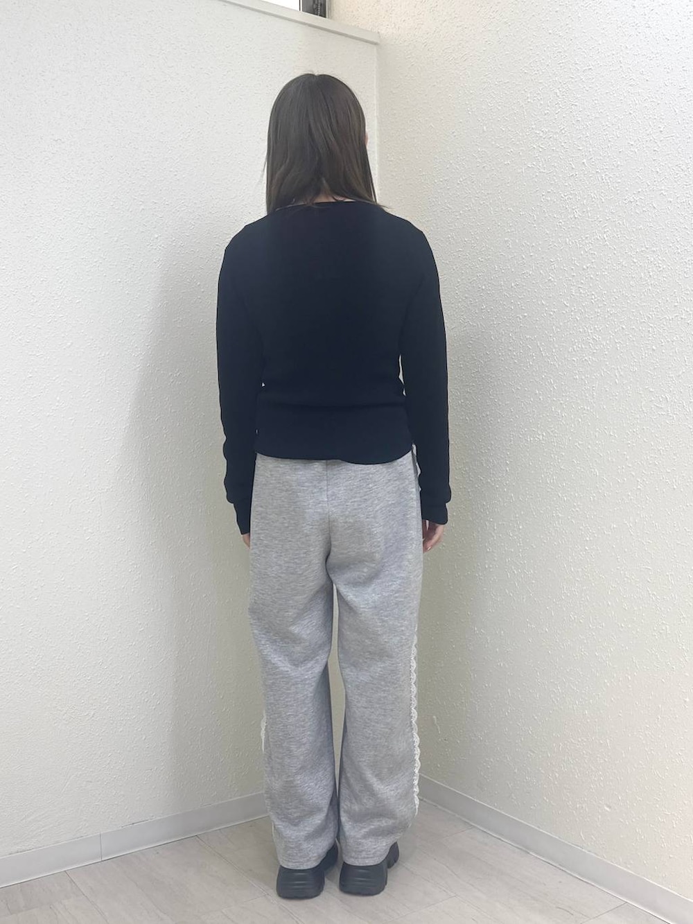 グレー系のスウェットパンツ、ブラック系のニット/セーター、イエロー系のTシャツ/カットソーを着用したレディースの冬コーディネートの2枚目の写真