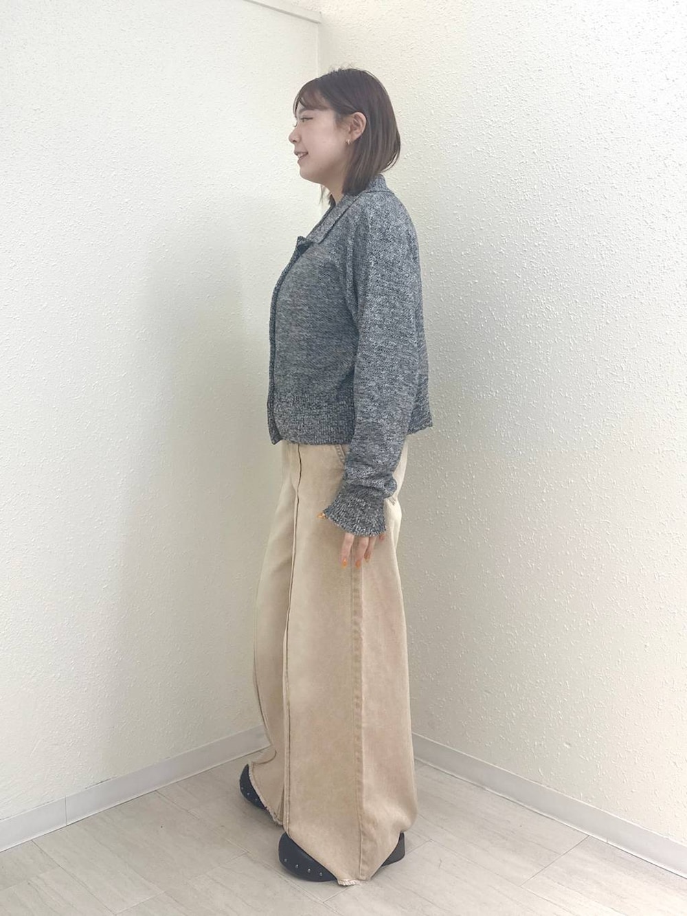 オレンジ系のデニムパンツ、ブラック系のサンダル、グレー系のカーディガン/ボレロを着用したレディースの春コーディネートの2枚目の写真