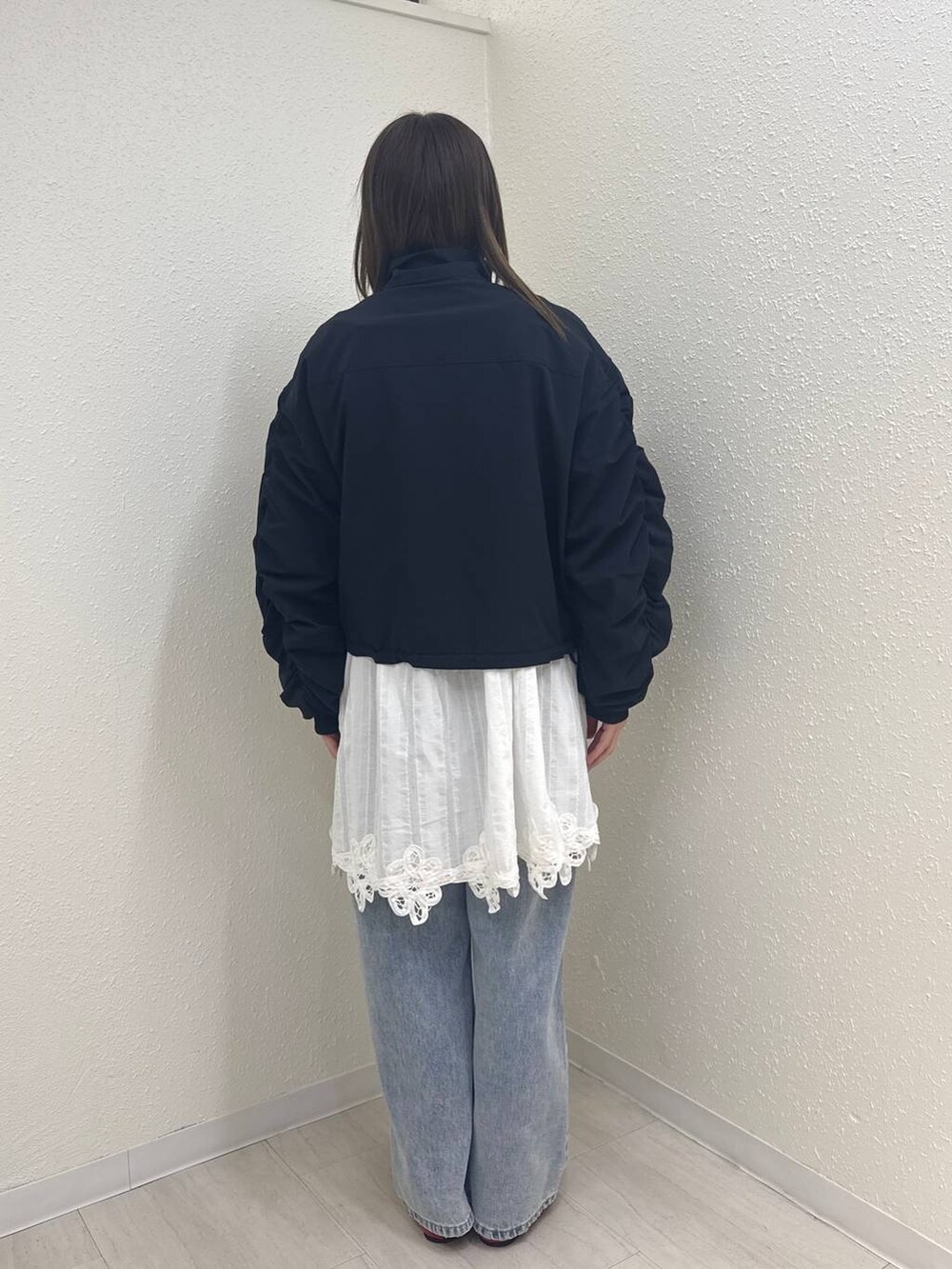 レッド系のパンプス、ブルー系のデニムパンツ、ブラック系のブルゾンを着用したレディースの春コーディネートの3枚目の写真