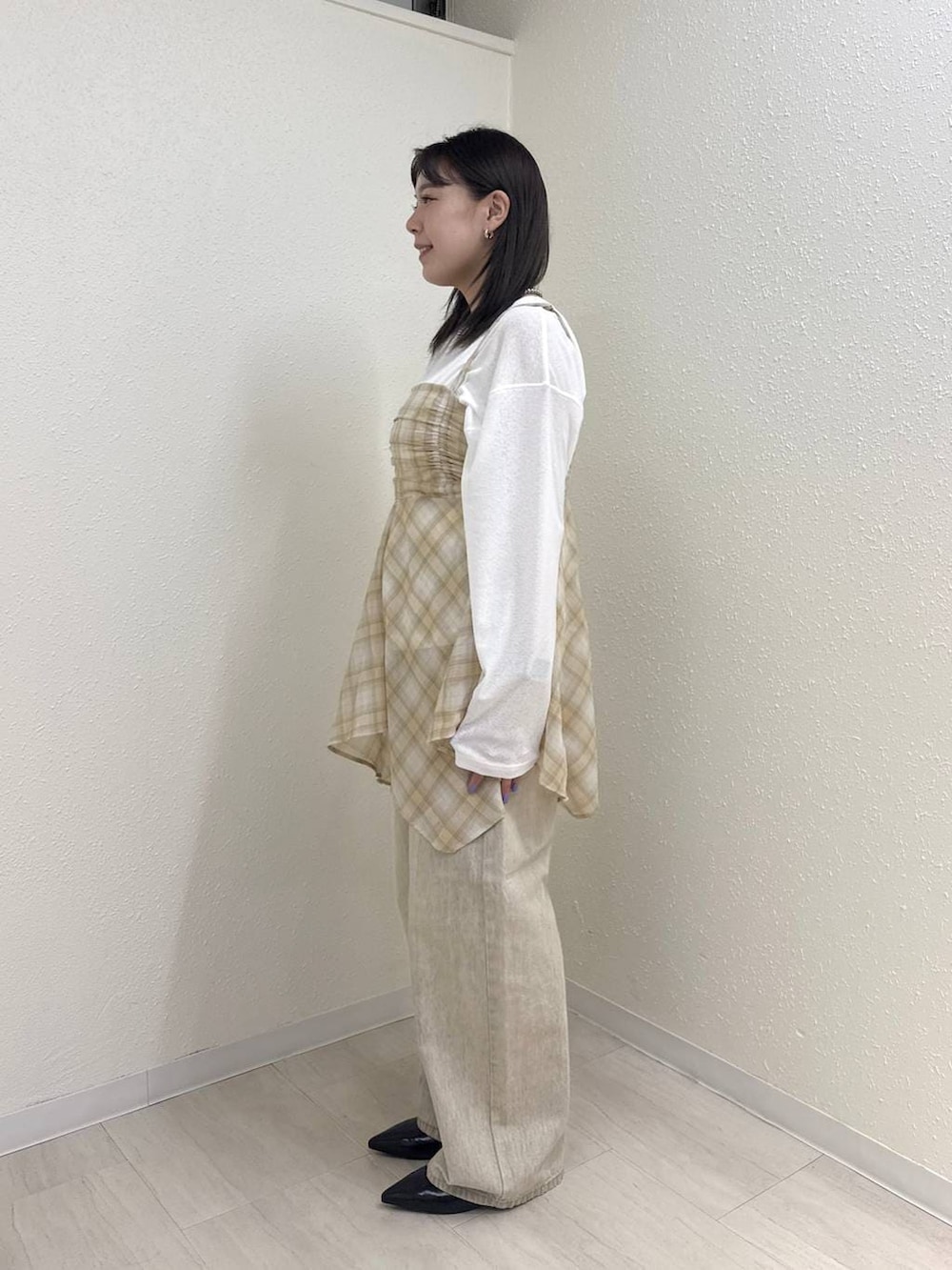 ホワイト系のTシャツ/カットソー、ブラック系のパンプス、ベージュ系のデニムパンツを着用したレディースの春コーディネートの3枚目の写真