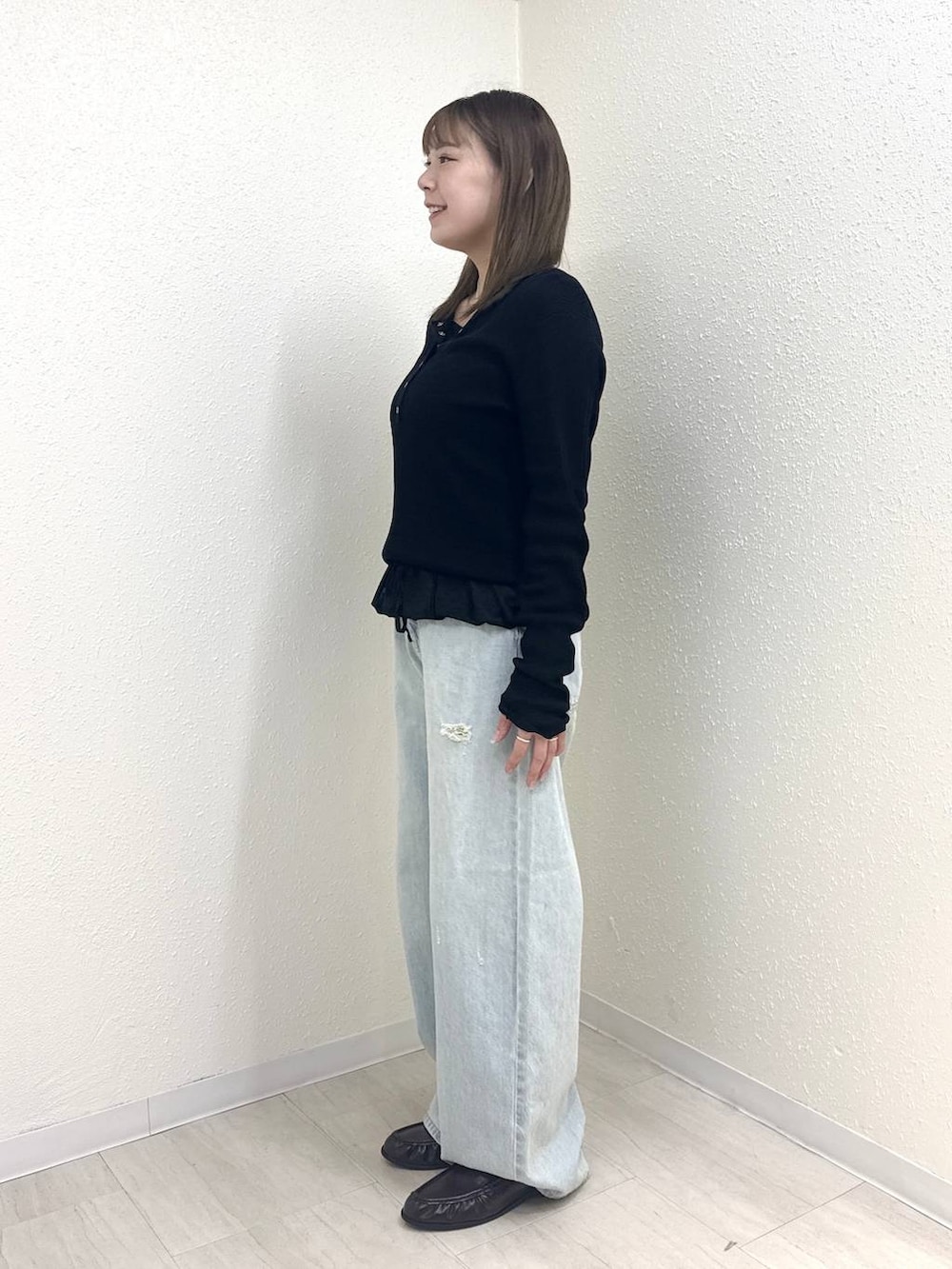 ブラック系のニット/セーター、ブルー系のデニムパンツ、ブラック系のTシャツ/カットソーを着用したレディースの春コーディネートの3枚目の写真