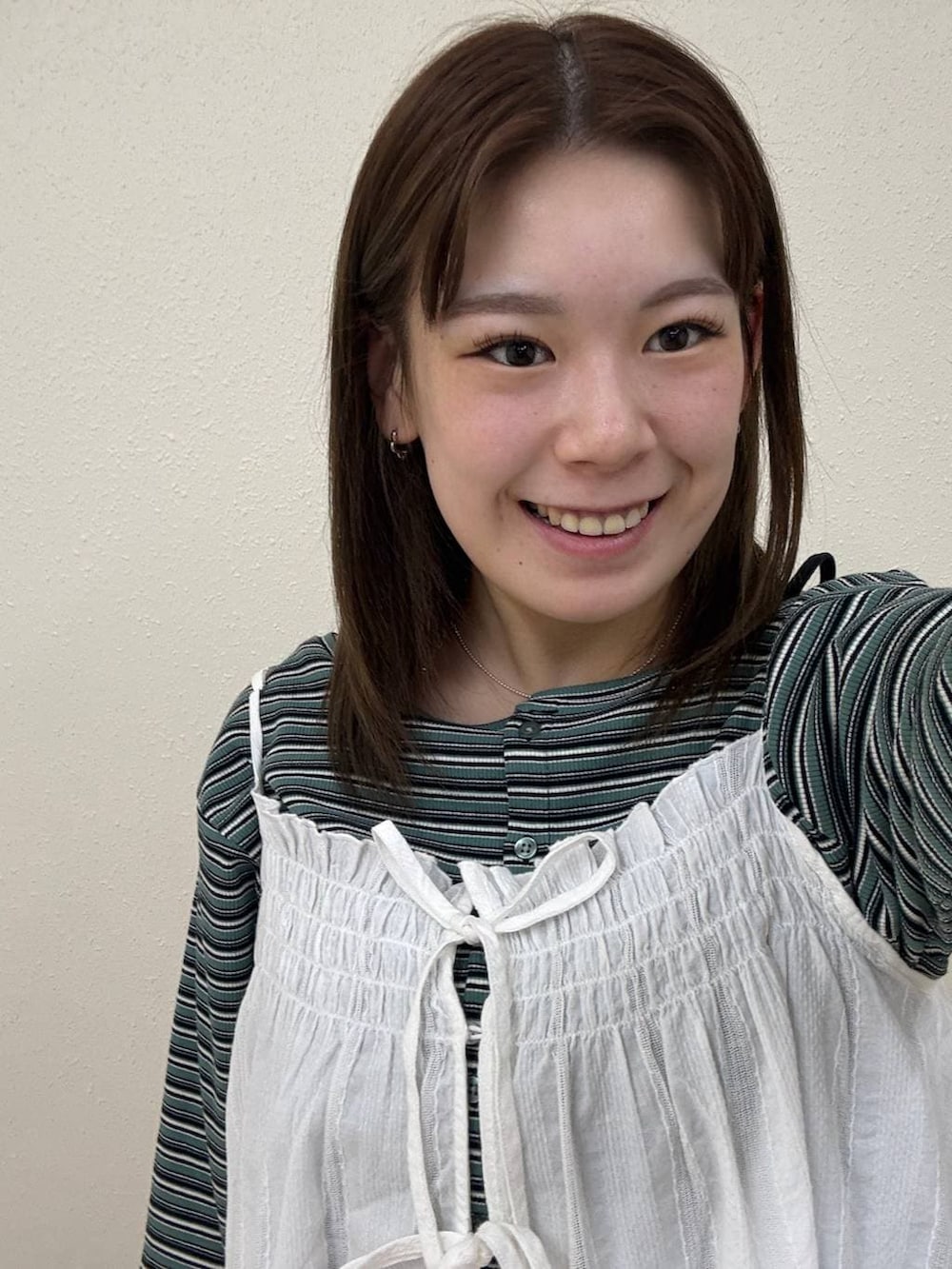 レッド系のパンプス、ブルー系のデニムパンツ、ホワイト系のワンピースを着用したレディースの春コーディネートの2枚目の写真