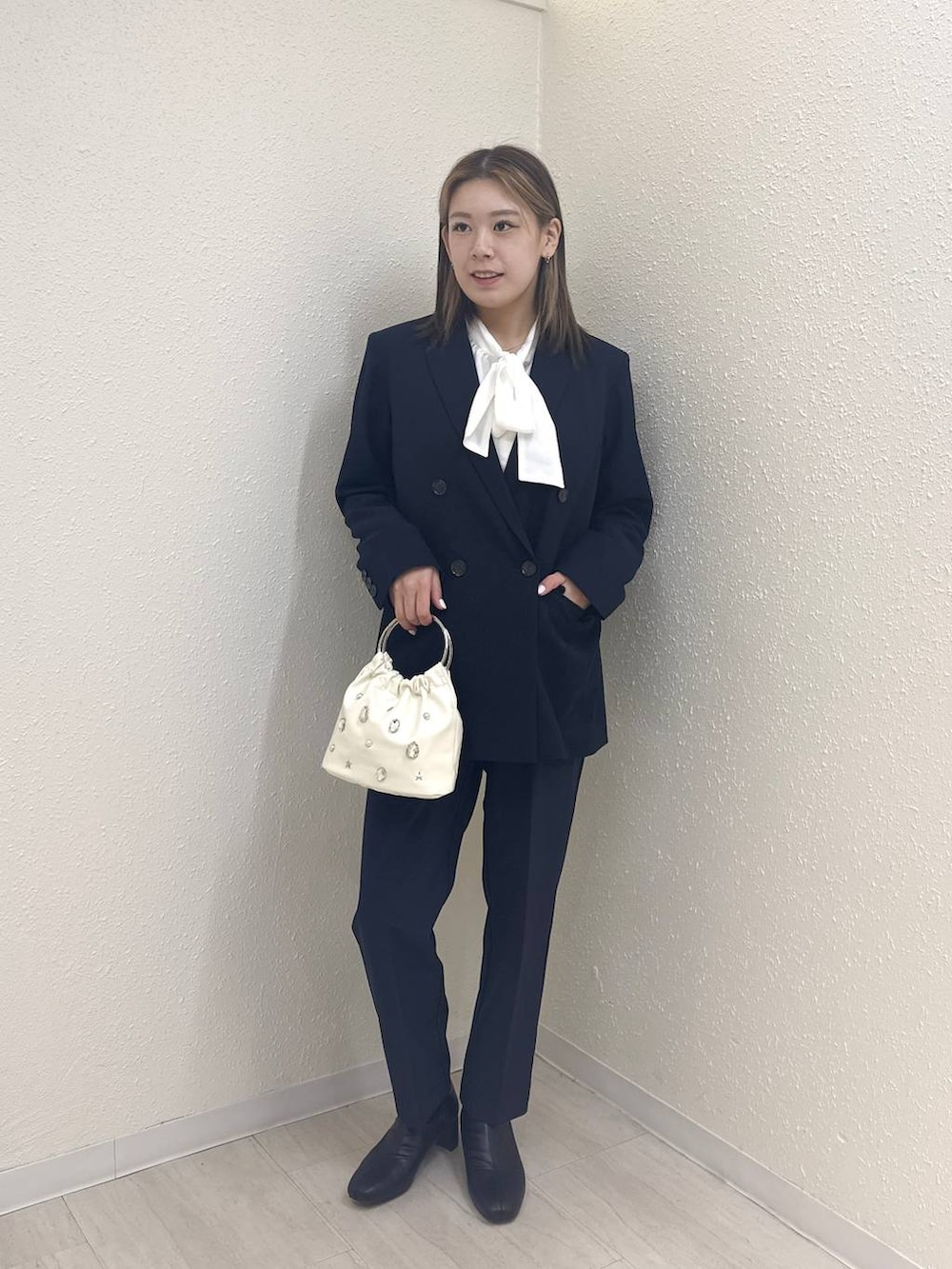 ブラック系のブーツ、ホワイト系のハンドバッグ、ブルー系のテーラードジャケットを着用したレディースの冬コーディネートの4枚目の写真