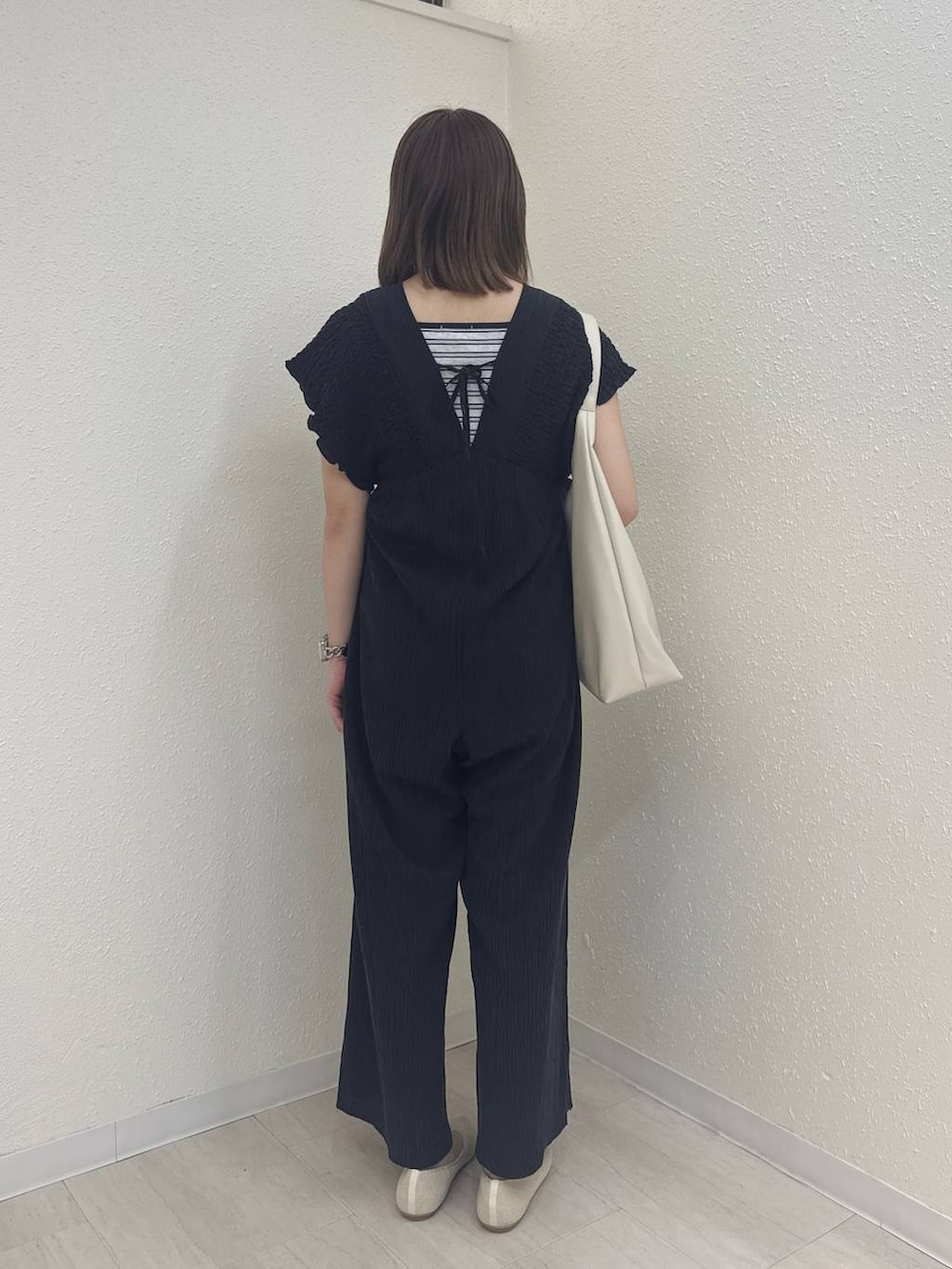 ホワイト系のショルダーバッグ、ブラック系のサロペット/オーバーオール、ホワイト系のパンプスを着用したレディースの春コーディネートの3枚目の写真