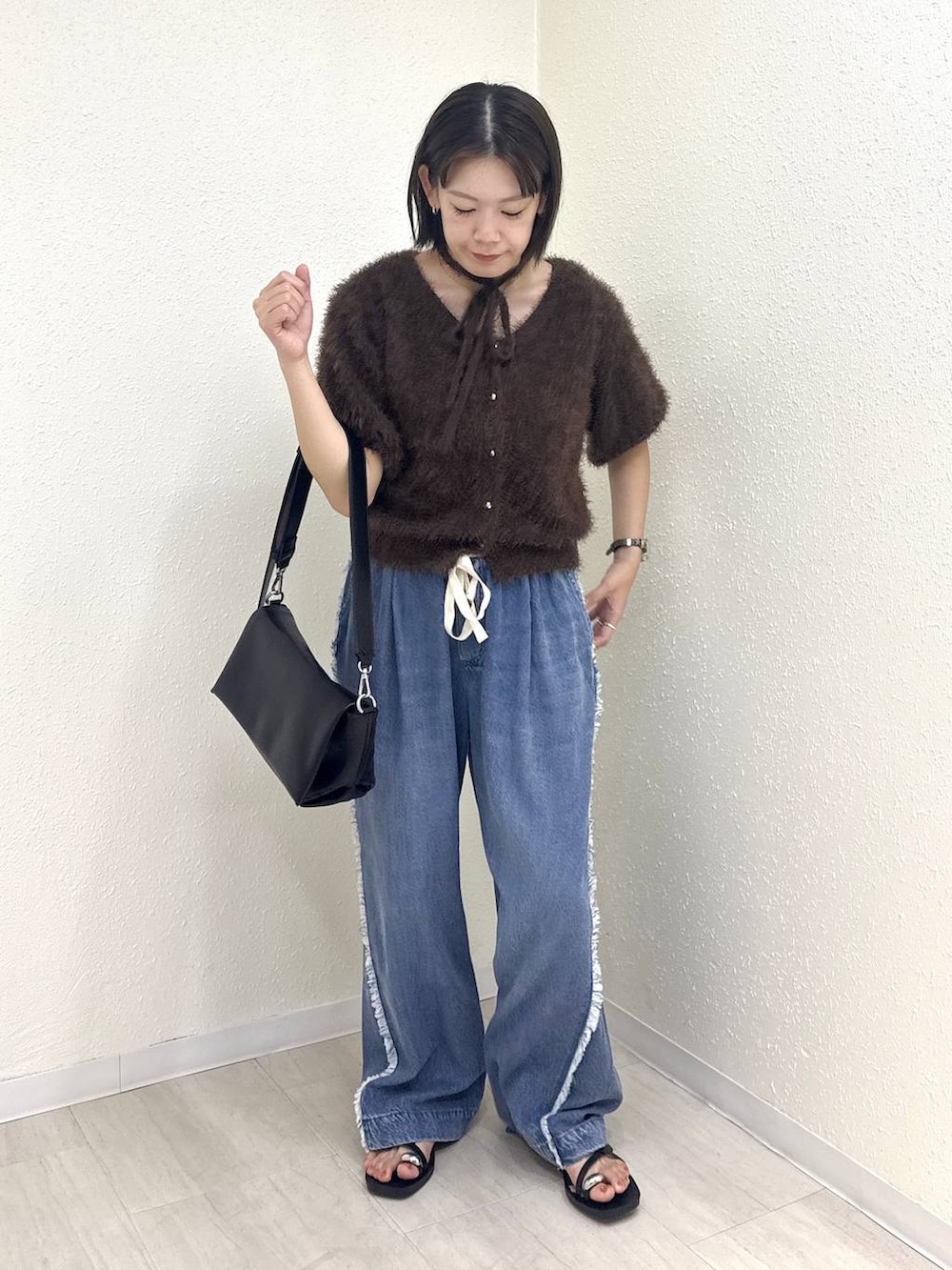 ブラック系のショルダーバッグ、ブラウン系のカーディガン/ボレロ、ブルー系のデニムパンツを着用したレディースの夏コーディネートの4枚目の写真