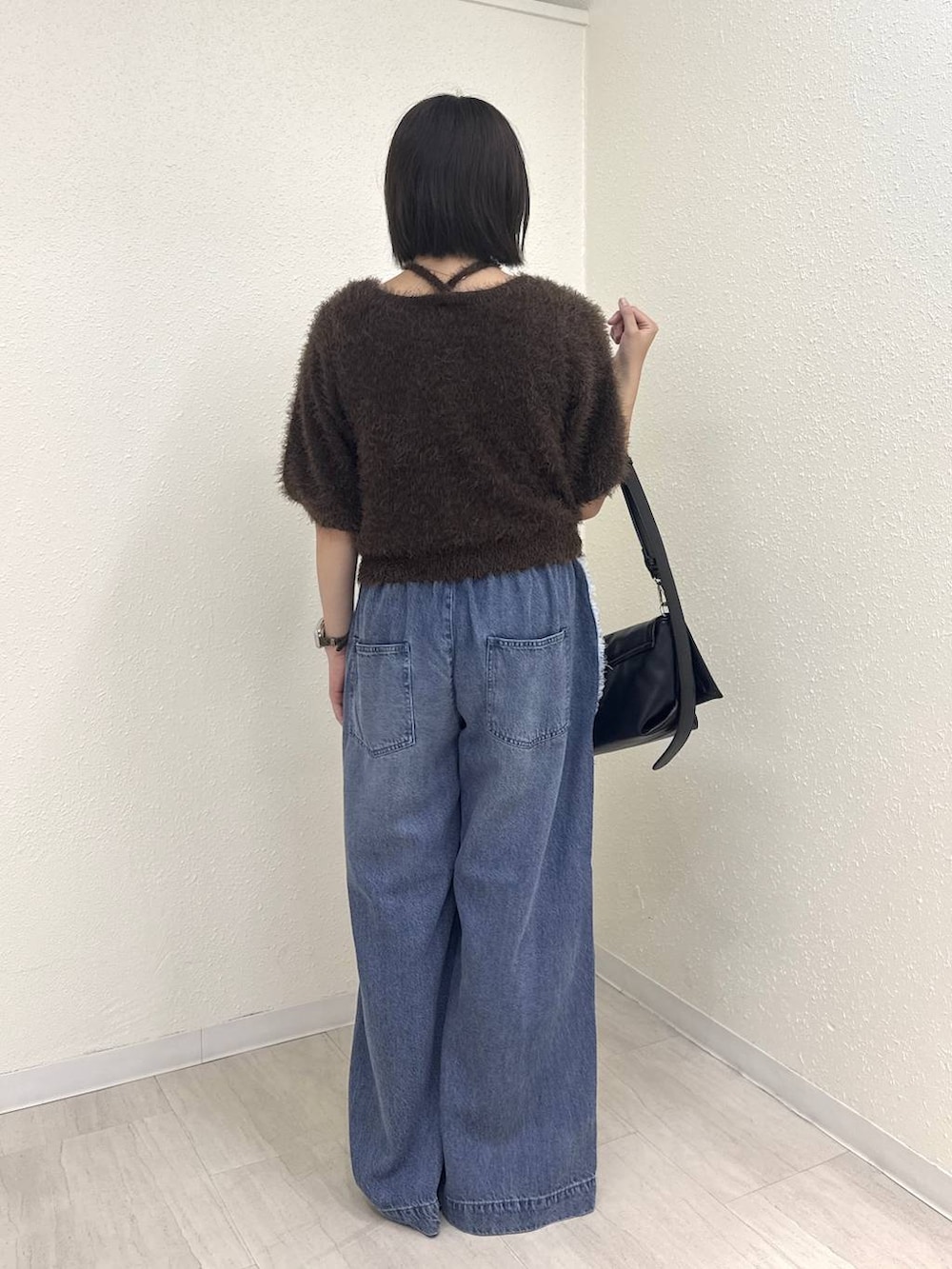 ブラック系のショルダーバッグ、ブラウン系のカーディガン/ボレロ、ブルー系のデニムパンツを着用したレディースの夏コーディネートの2枚目の写真